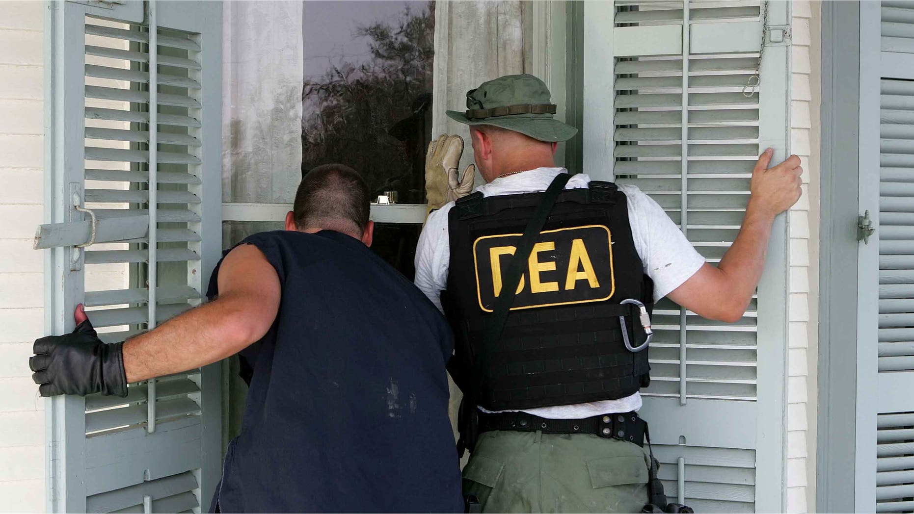 NEW ORLEANS - SEPTEMBER 10: DEA agents look into a window of a house in the while searching for victims in the Ninth Ward district September 10, 2005 in New Orleans, Louisiana. Rescue crews continue to search homes searching for hold outs and deceased people. (Photo by Justin Sullivan/Getty Images)