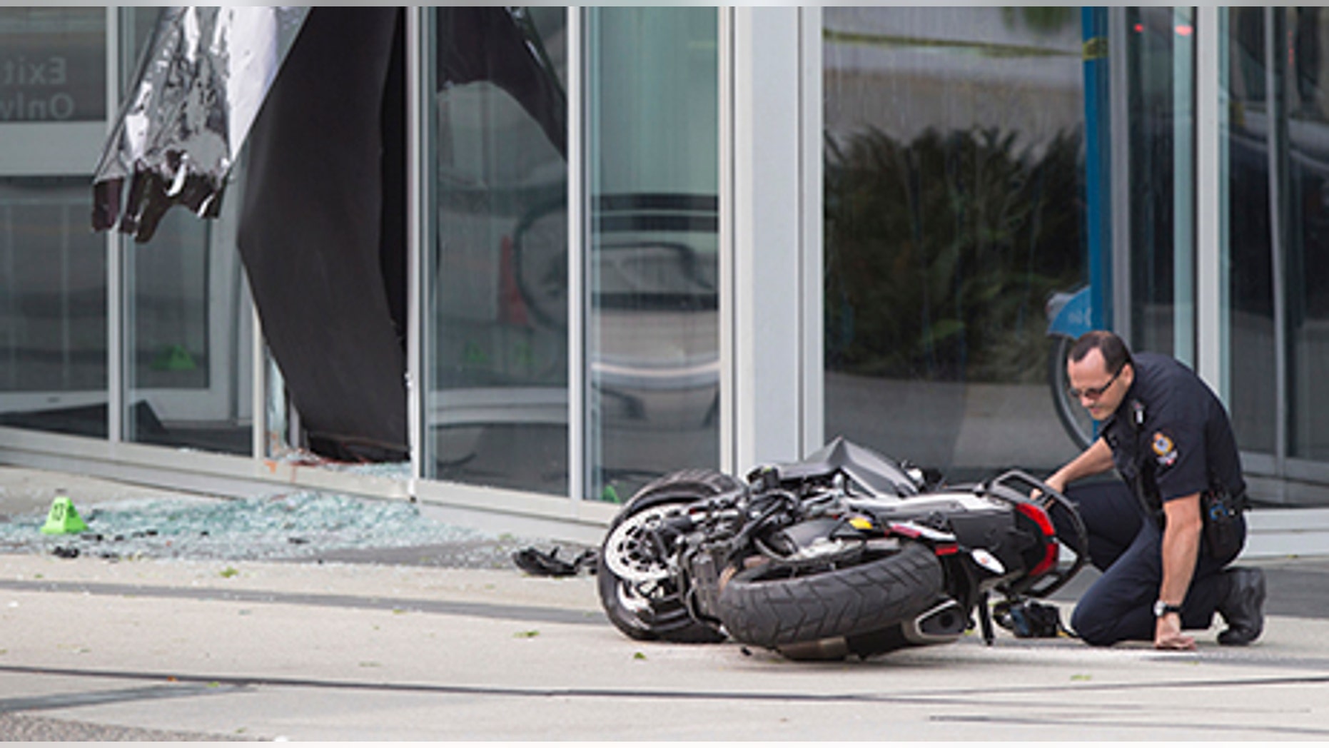A police officer examines a motorcycle after a female stunt driver working on the movie "Deadpool 2" died after a crash on set, in Vancouver, B.C., on Aug. 14, 2017. Vancouver police say the driver was on a motorcycle when the crash occurred on the movie set on Monday morning.