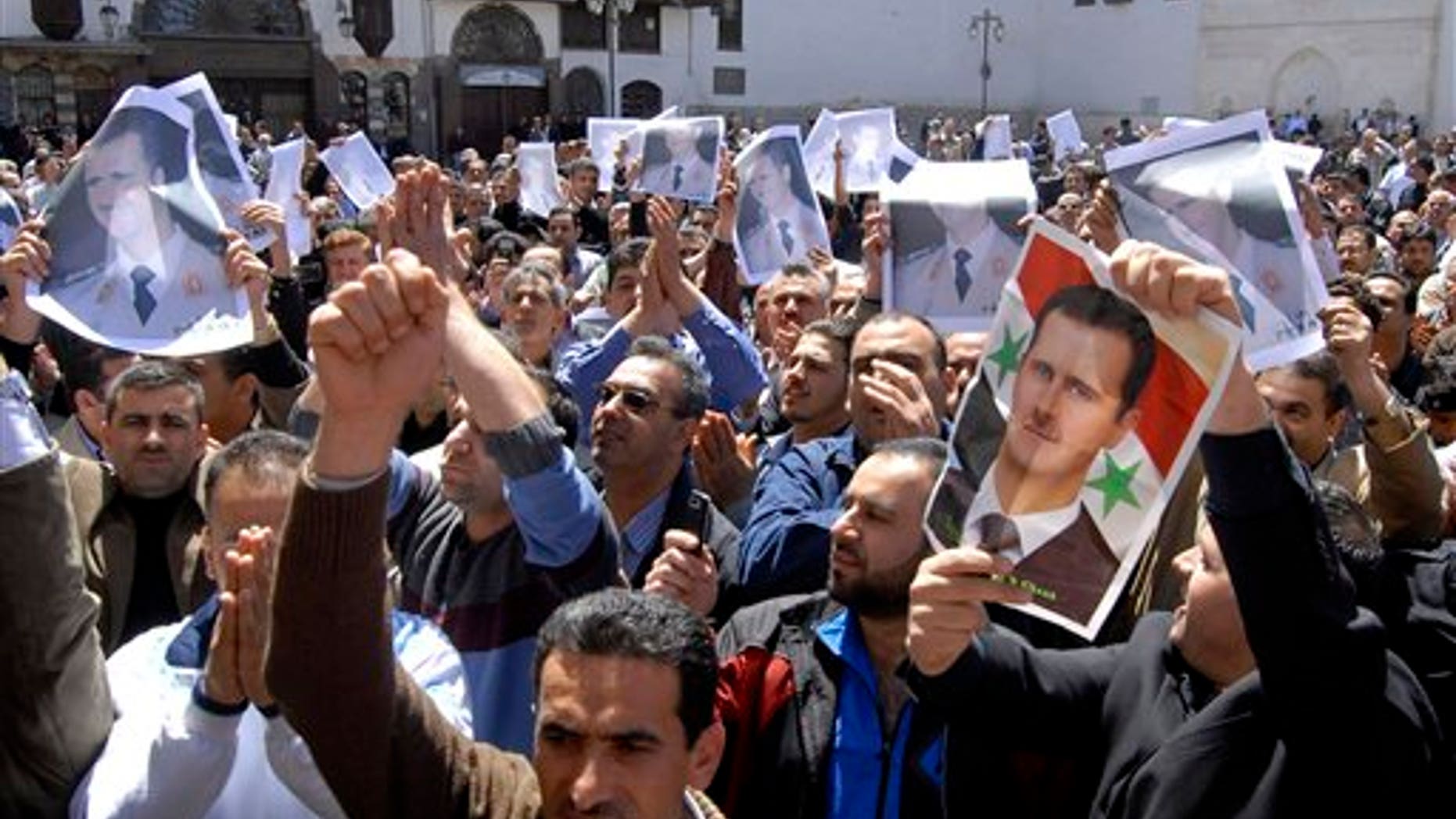 April 15: Syrian pro-government protesters carry pictures of Syrian President Bashar Assad as they shout slogans after Friday prayers outside the Omayyad Mosque in Damascus, Syria. (AP)