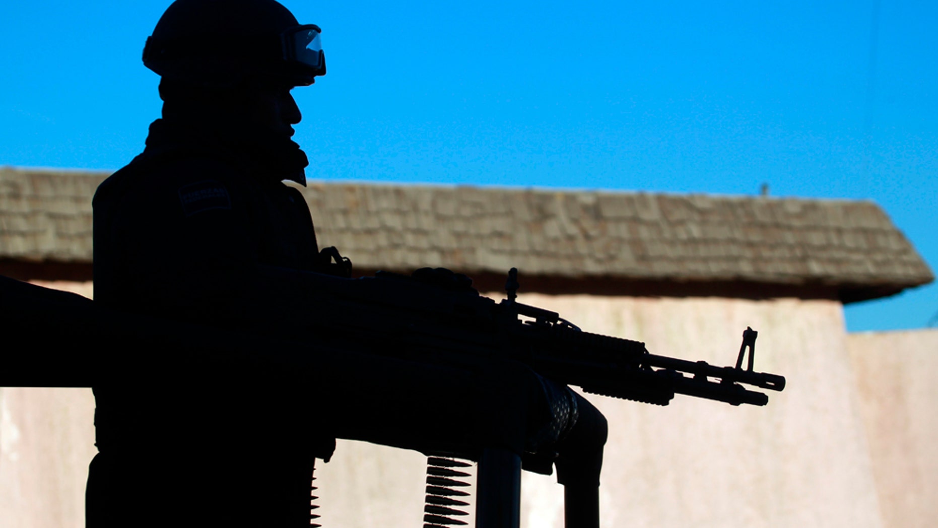 A federal police officer stands on a vehicle as he guards the area near a car where two people lie dead in the heavily guarded "safe" zone, the PRONAF, in Ciudad Juarez, Mexico, Monday Dec. 13, 2010. According to local media reports, the car was driven by a woman who was trying to get medical attention for her two cousins after they were shot at another location. The two boys, age 11 and 17, died on the way to the hospital. (AP Photo/Dario Lopez-Mills)