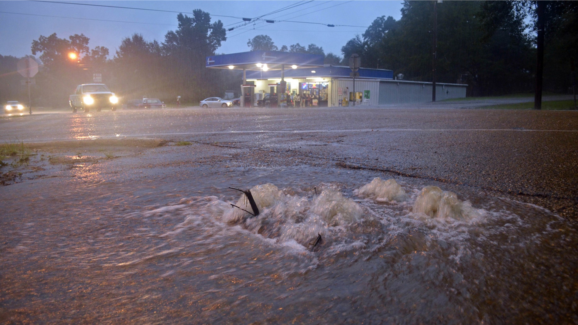 Aug. 12, 2016: Floodwaters surge from a crack in the parking lot on the corner of highways 584 and 51 in Osyka, Miss.