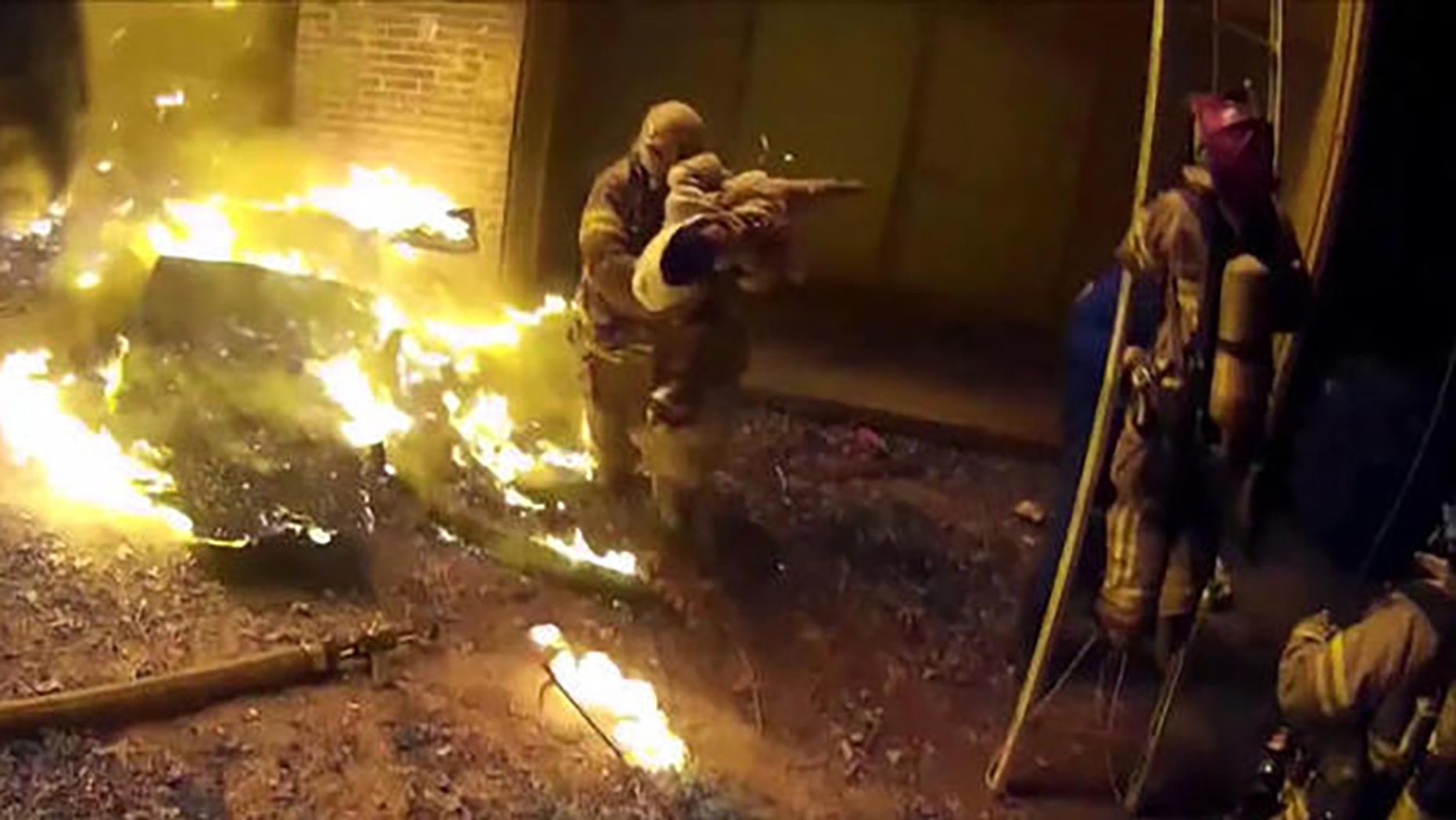 Image shows Cpt. Scott Stroup rescuing a child thrown from a burning building on Jan. 3.
