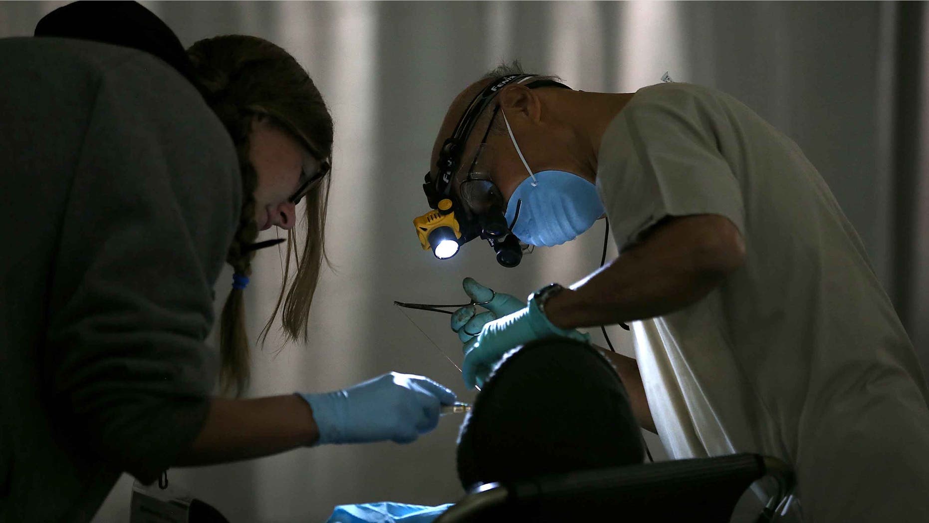 SAN FRANCISCO, CA - APRIL 23: A dentist performs a dental procedure during the Bridges to Health medical and dental clinic on April 23, 2014 in San Francisco, California. Hundreds of people lined up for the first of four free medical and dental clinics hosted by the Bridges to Health in San Francisco and Oakland. More than 500 healthcare professionals and volunteers will perform no-cost services that include root canals, fillings, women's health services and STD/HIV screening. (Photo by Justin Sullivan/Getty Images)