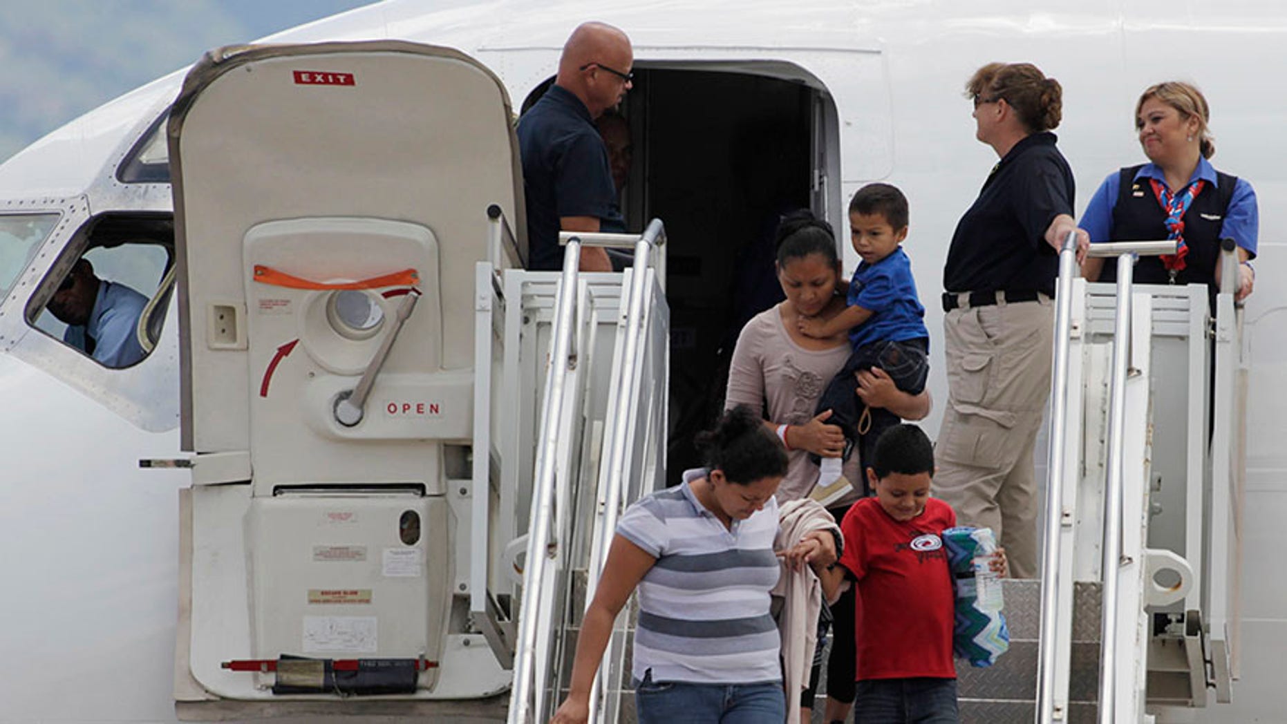 Women hold their children while disembarking from a plane at the Soto Cano military base in Comayagua August 11, 2014. The plane carrying 11 women and 14 children landed at the base after they had been deported from the U.S. While the White House says the number of Central American child migrants crossing the U.S. border has fallen sharply, the big unanswered question remains why. The U.S. government has pointed to the seasonal weather. However, Reuters reporting in southern Mexico and Central America shows it is due to a combination of factors, including tighter border policing, horror tales told by deportees who grappled with drug gangs, an advertising blitz touting the dangers of making the journey and the high-profile arrests of several human smugglers, or coyotes. Picture taken August 11. To match Insight USA-IMMIGRATION/DECLINE REUTERS/Jorge Cabrera (HONDURAS - Tags: SOCIETY IMMIGRATION POLITICS MILITARY TRANSPORT) - RTR422BX