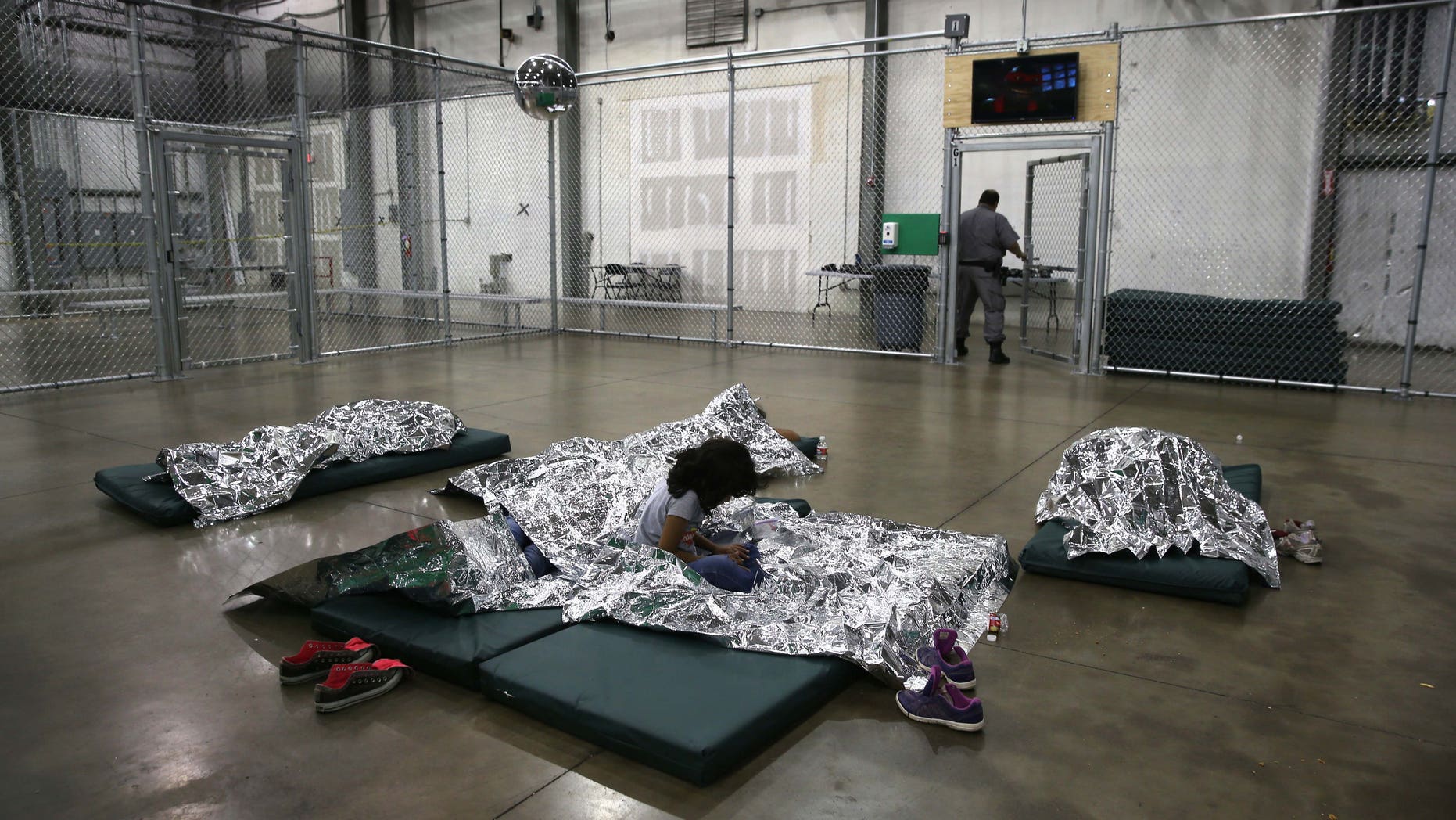 MCALLEN, TX - SEPTEMBER 08: A girl from Central America rests on thermal blankets at a detention facility run by the U.S. Border Patrol on September 8, 2014 in McAllen, Texas. The Border Patrol opened the holding center to temporarily house the children after tens of thousands of families and unaccompanied minors from Central America crossed the border illegally into the United States during the spring and summer. Although the flow of underage immigrants has since slowed greatly, thousands of them are now housed in centers around the United States as immigration courts process their cases. (Photo by John Moore/Getty Images)