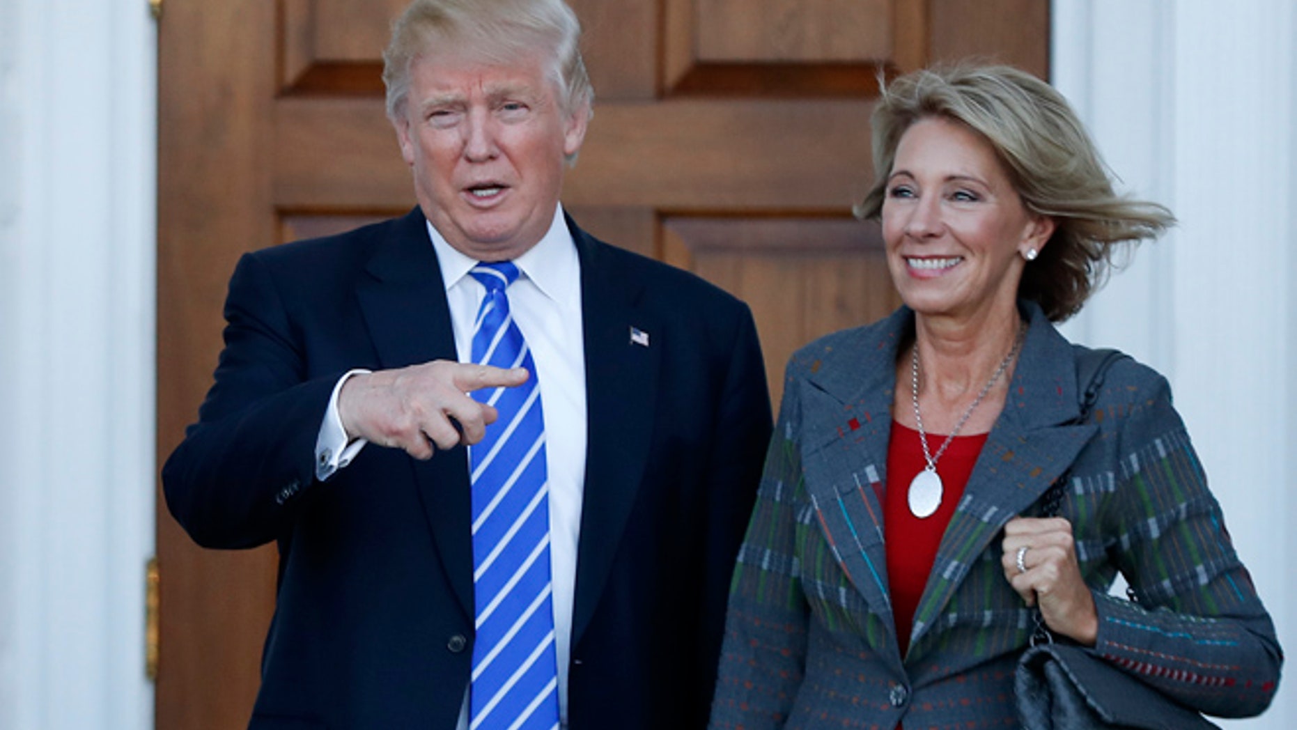 FILE - In this Nov. 19, 2016 photo, President-elect Donald Trump and Betsy DeVos pose for photographs at Trump National Golf Club Bedminster clubhouse in Bedminster, N.J. Trump has chosen charter school advocate DeVos as Education Secretary in his administration.