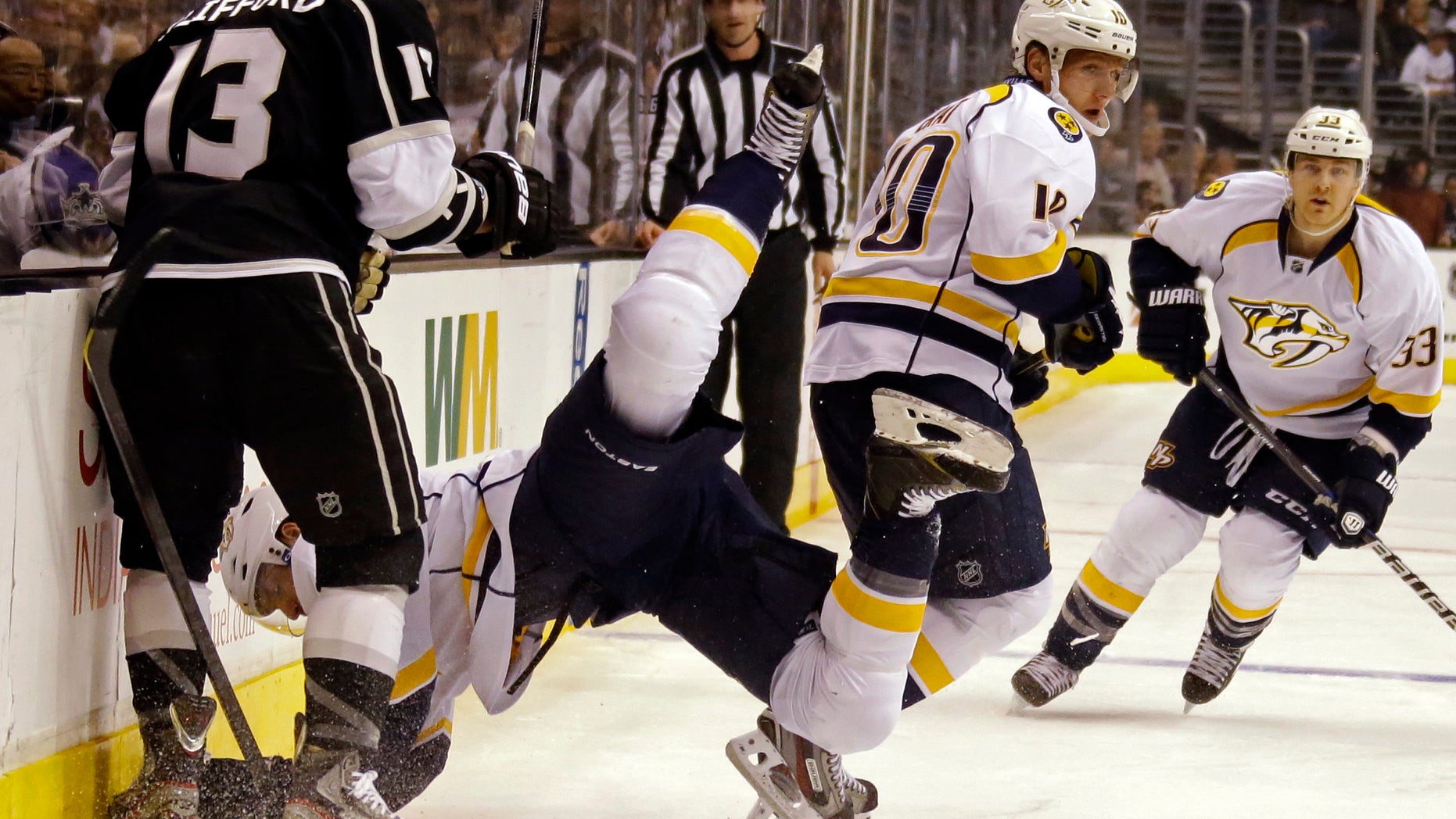 Nashville Predators defenseman Kevin Klein (8) goes flying while left winger Martin Erat (10) and center Colin Wilson (33) chase the puck as Los Angeles Kings left winger Kyle Clifford watches at left during the first period of an NHL hockey game in Los Angeles Thursday, Jan. 31, 2013. (AP Photo/Reed Saxon)