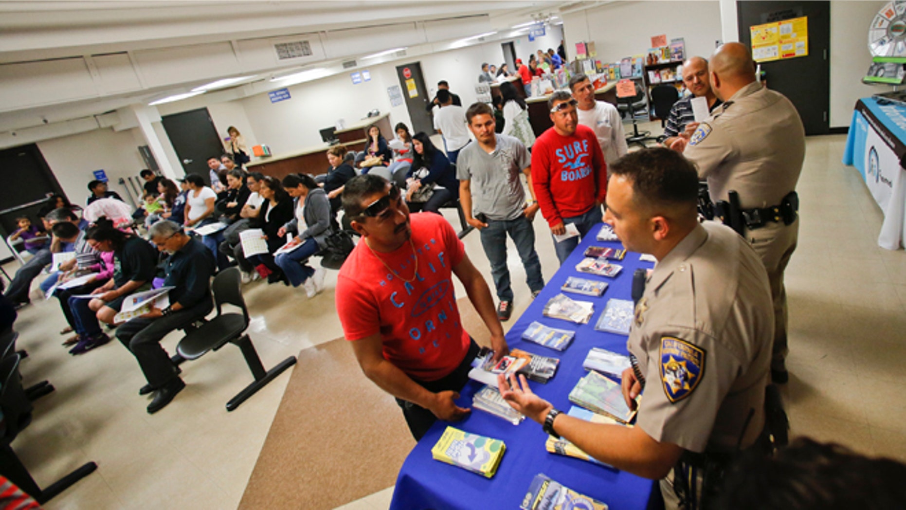 FILE - In this Wednesday, April 23, 2014 file photo, California Highway Patrol officers Armando Garcia, right, and Ray Patton explain to immigrants the process of getting a drivers license during an information session at the Mexican Consulate, in San Diego. California is gearing up to start issuing driverâs licenses to immigrants in the country illegally in a bid to make the roads safer that could also give more than a million people access to state-issued identification. (AP Photo/Lenny Ignelzi,File)