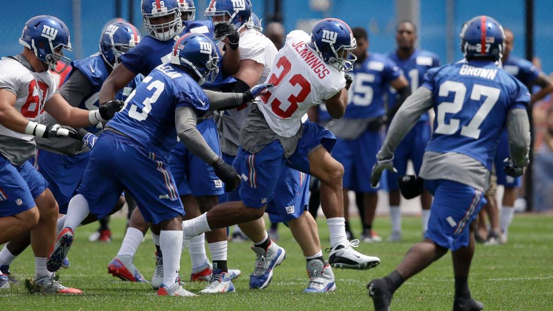 New York Giants' Rashad Jennings (23), center, runs through traffic during NFL football camp in East Rutherford, N.J., Thursday, July 24, 2014. (AP Photo/Seth Wenig)