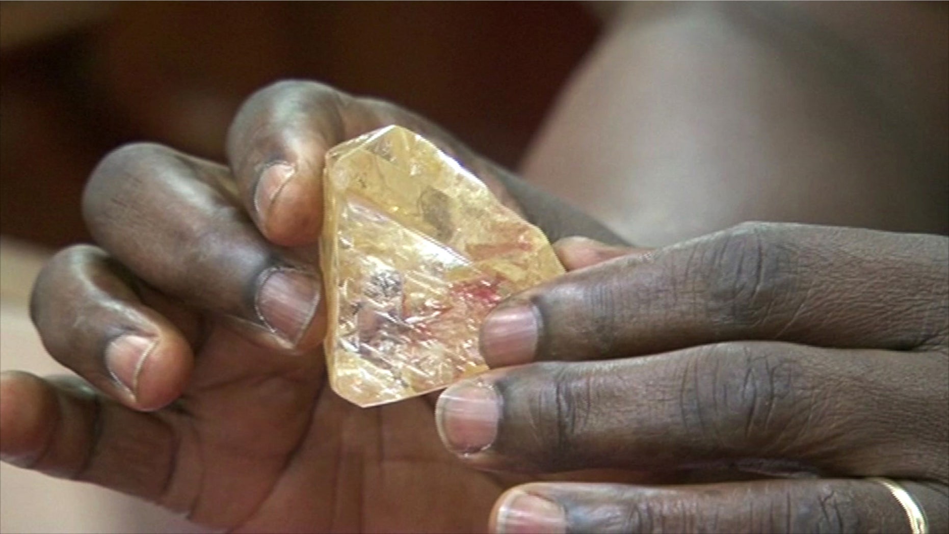 In this photo taken from video footage, Sierra Leone's President Ernest Bai Koroma hands a diamond during a meeting with delegates of Kono district, where the gem was found, at the presidential office in Freetown, Sierra Leone, Thursday, March 16, 2017