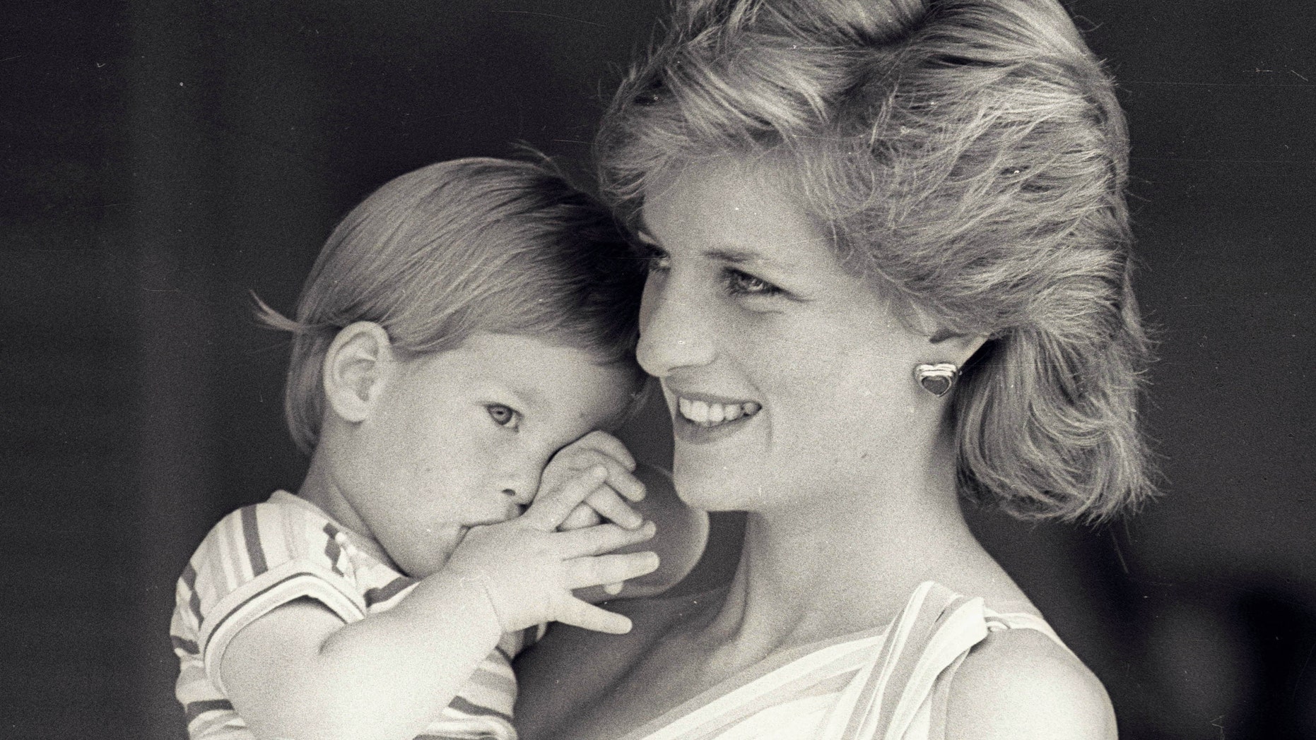 August 9, 1988. Young Prince Harry tries to hide behind his mother Princess Diana during a morning picture session at Marivent Palace.