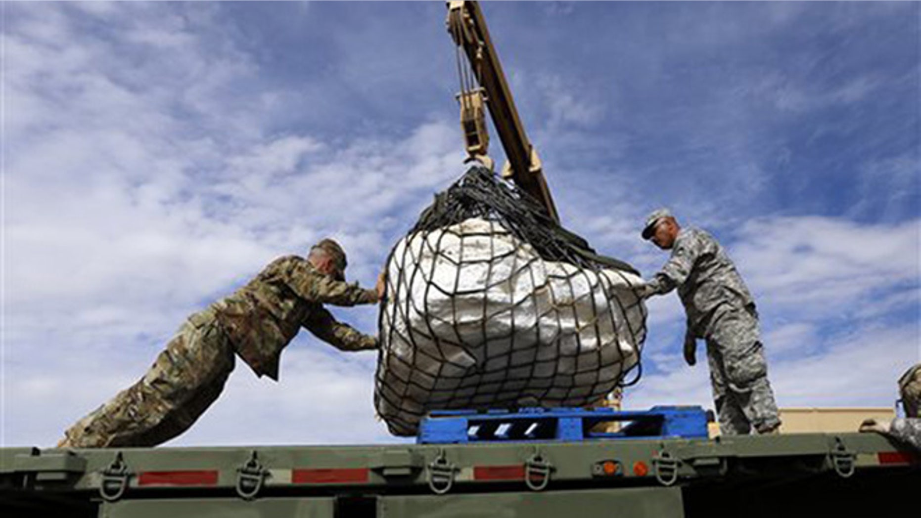 Sgt. James Ray and Staff Sgt. Noe Amador secure the remains of a Pentaceratops, Thursday, Oct. 29, 2015, to a flatbed trailer in the Bisti-De-Na-Zin Wilderness area south of Farmington, N.M. The fossils are encapsulated in heavy plaster jackets. (Jon Austria/The Daily Times via AP)