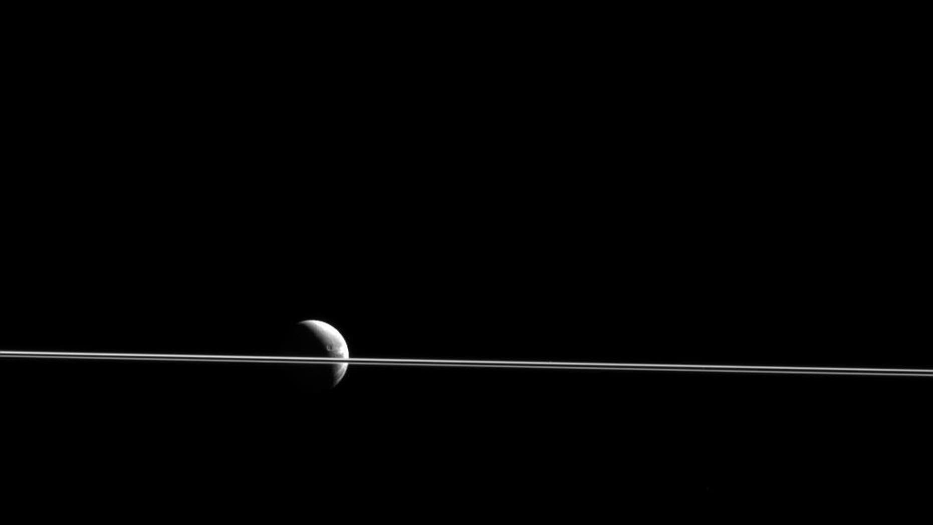 Dione appears cut in two by Saturn's razor-thin rings, seen nearly edge-on in a view from NASA's Cassini spacecraft. This scene was captured from just 0.02 degrees above the ring plane. (NASA/JPL-Caltech/Space Science Institute)