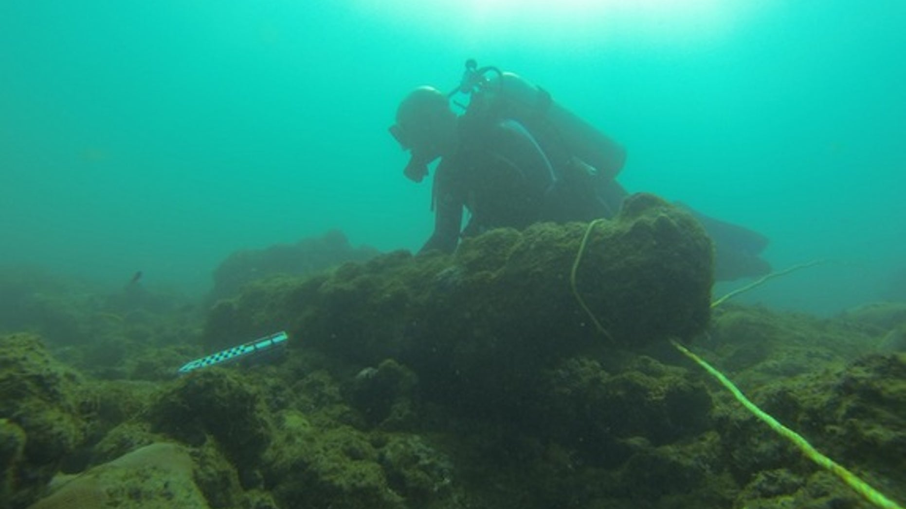 A diver measures a cannon found at the wreck site in Tobago's Rockley Bay.