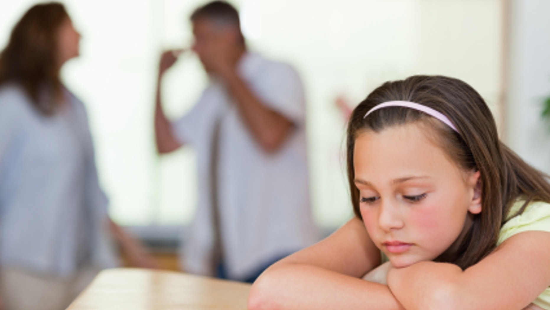 Sad looking girl with her fighting parents behind her