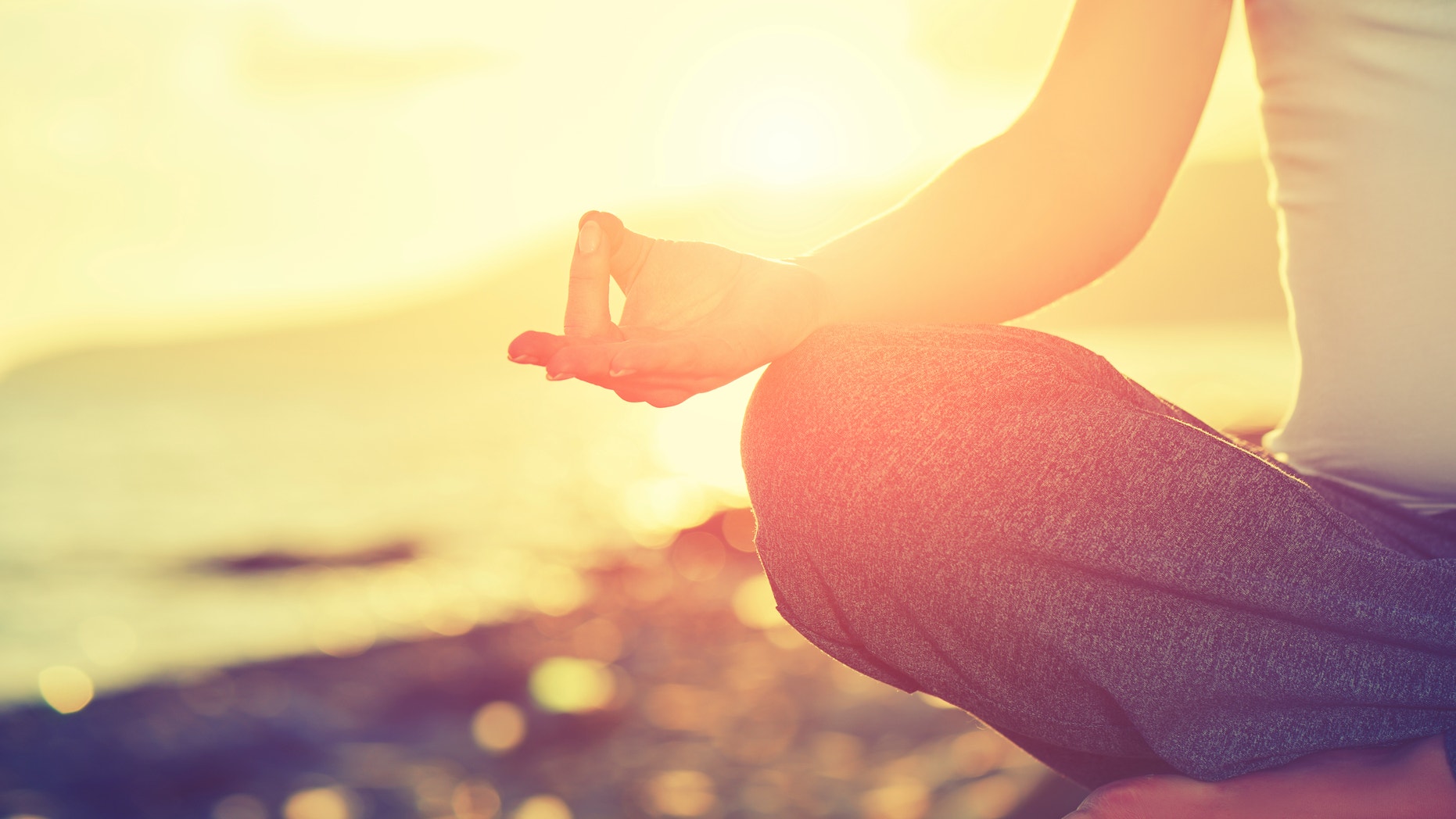 Yoga concept. hand woman practicing lotus pose on the beach at sunset