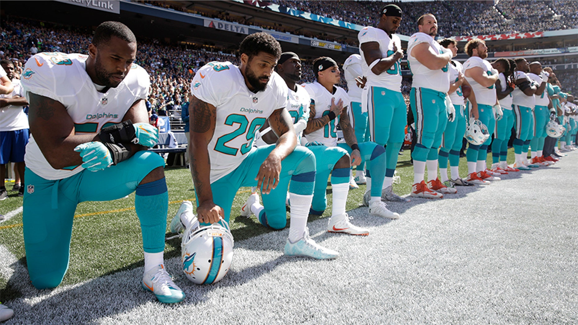 In this Sept. 11, 2017 file photo, from left, Miami Dolphins' Jelani Jenkins, Arian Foster, Michael Thomas, and Kenny Stills, kneel during the singing of the national anthem before an NFL football game against the Seattle Seahawks in Seattle.