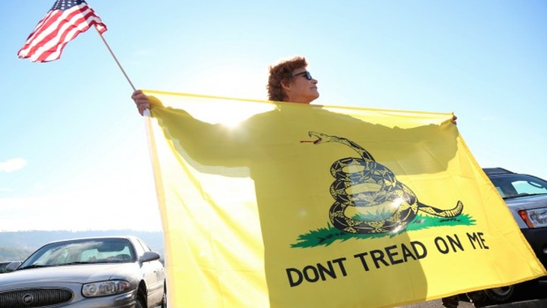 FILE -- Oct. 9, 2015: Leslie Corp holds up an American flag and the Gadsden flag in Roseburg, Ore.