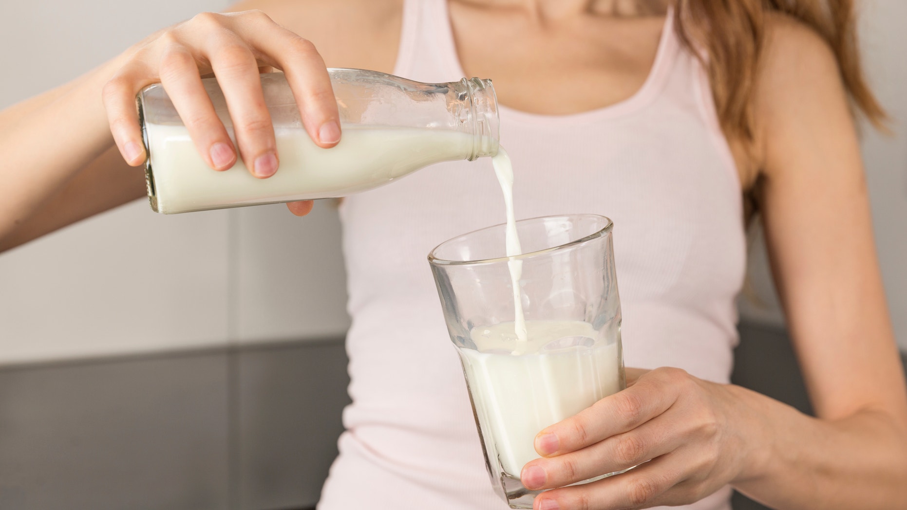 A woman pouring milk into a glass.