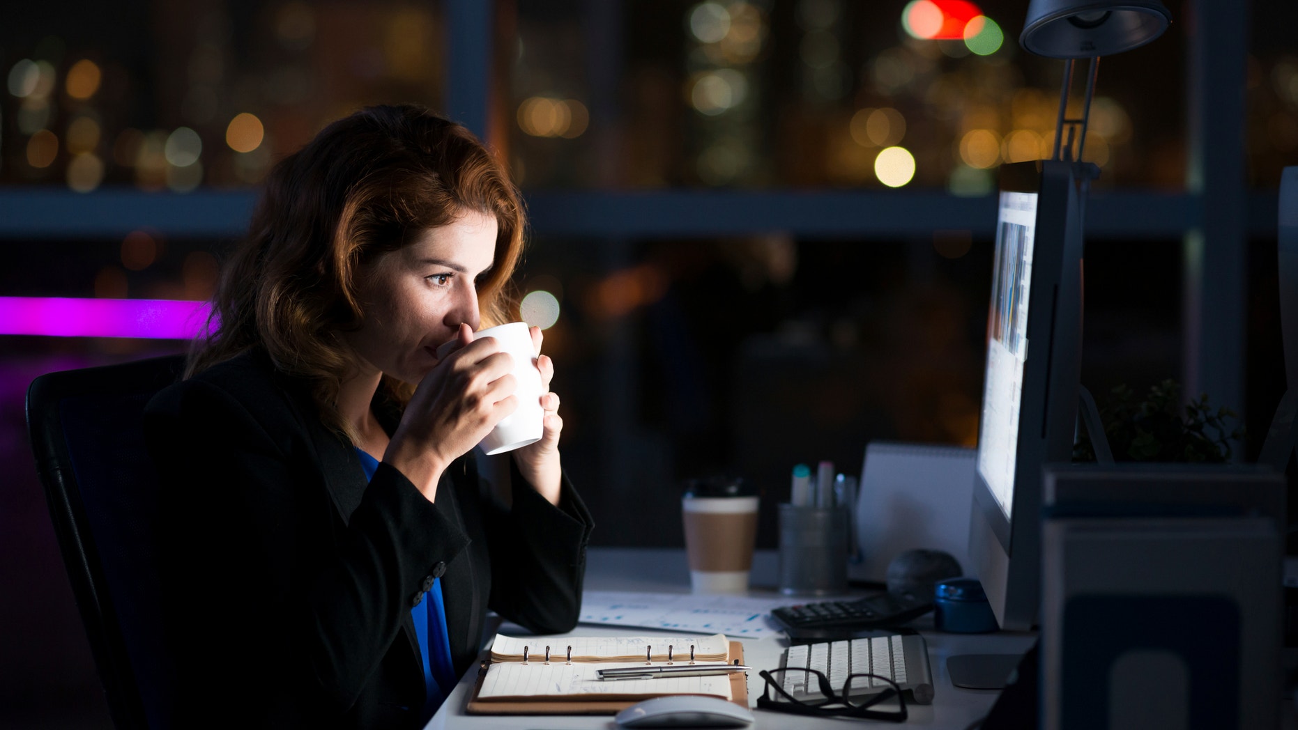 Business woman drinking coffee to get some energy for working overtime