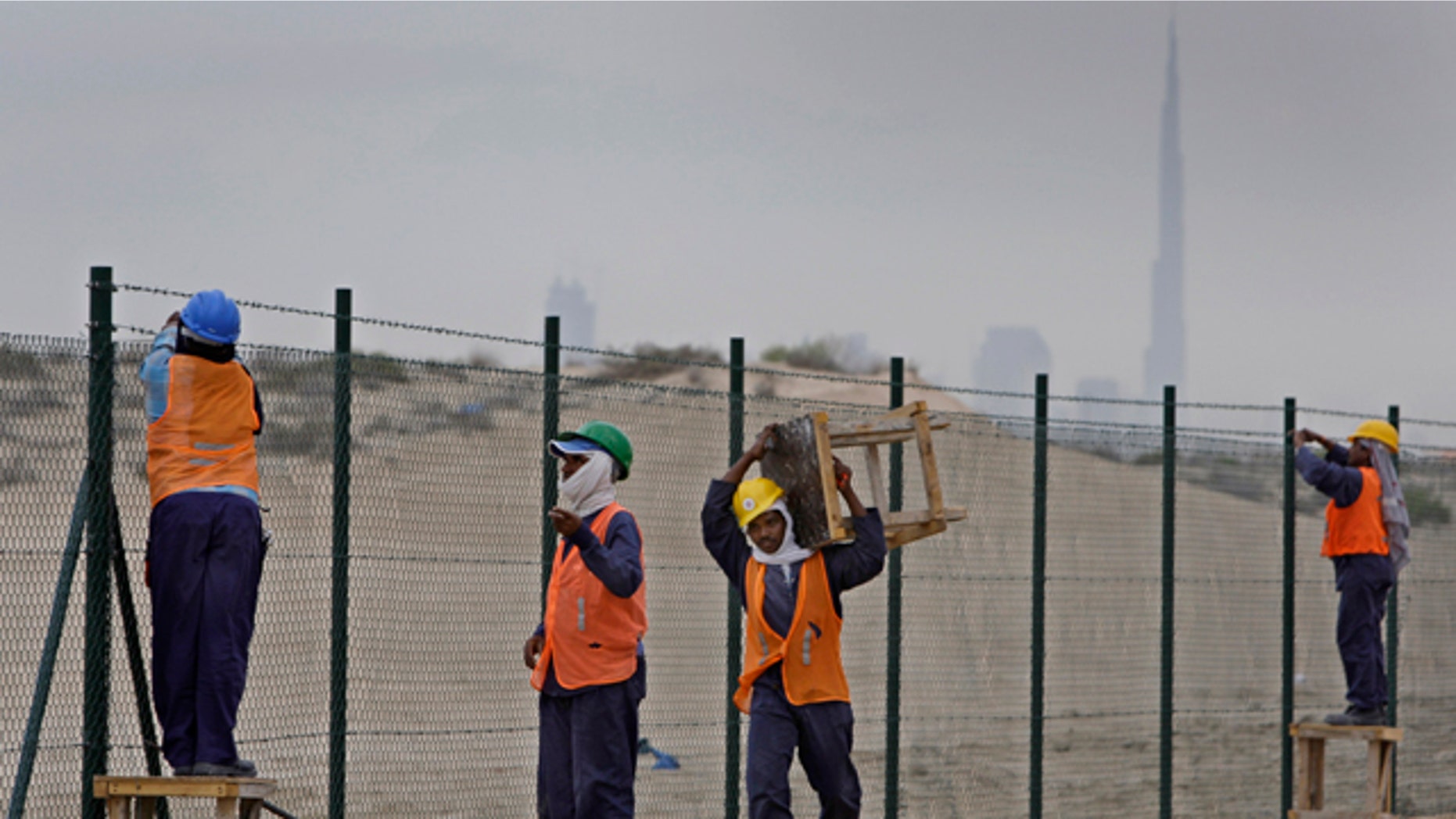 Nov. 27: With a view of world's tallest tower Burj Khalifa in background, Asian laborers fix new fence around a horse race track at Al Barsha district in Dubai.