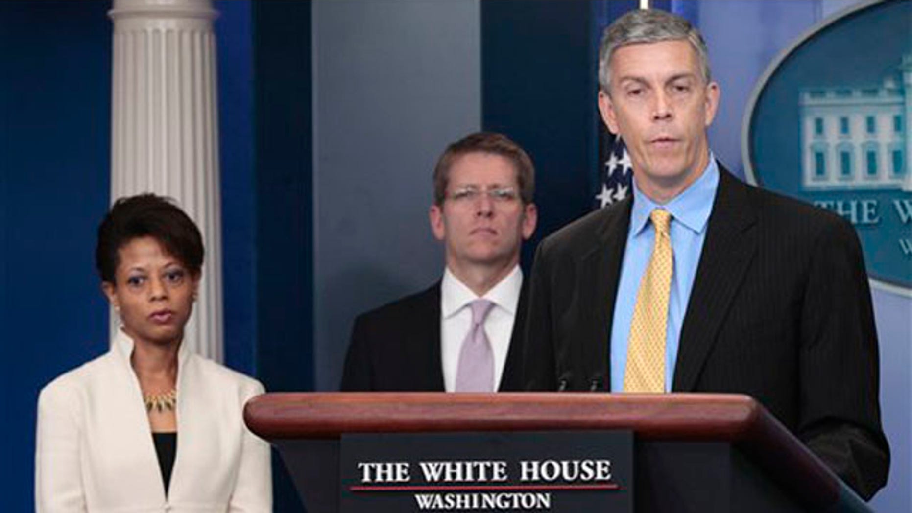Education Secretary Arne Duncan, right, accompanied by White House Press Secretary Jay Carney, center, and Domestic Policy Council Director Melody Barnes, speaks at the White House in Washington Aug. 8.