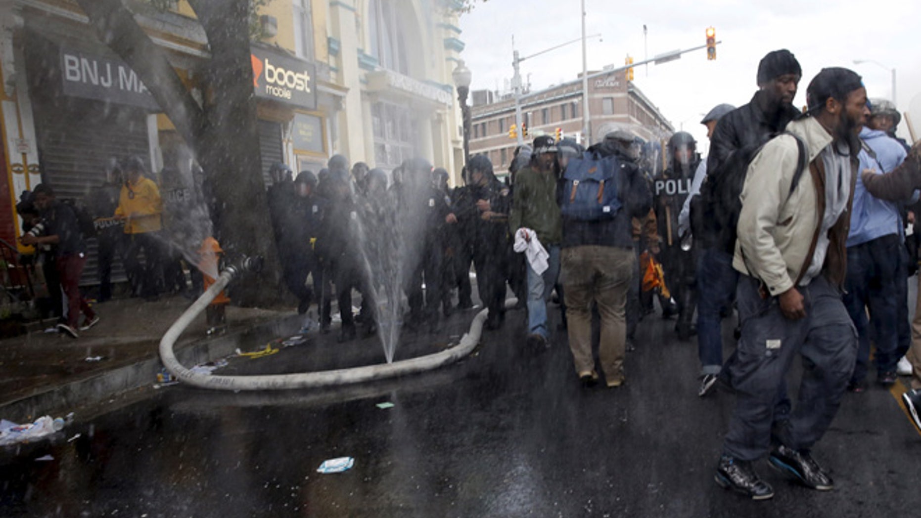 APRIL 2015: A fire hose cut by rioters sprays water into the air as protesters and a line of police move in at the site of a burning CVS drug store during clashes in Baltimore