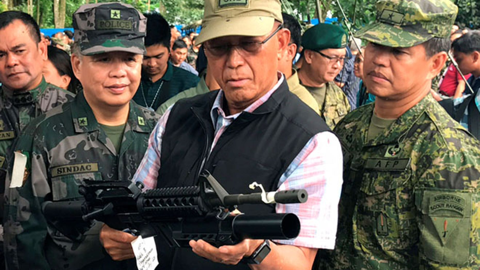 June 8: Philippines Defense Secretary Delfin Lorenzana (C) inspects a high-powered firearm seized from various hideouts of Islamist militants during their visit at a military camp in Marawi city