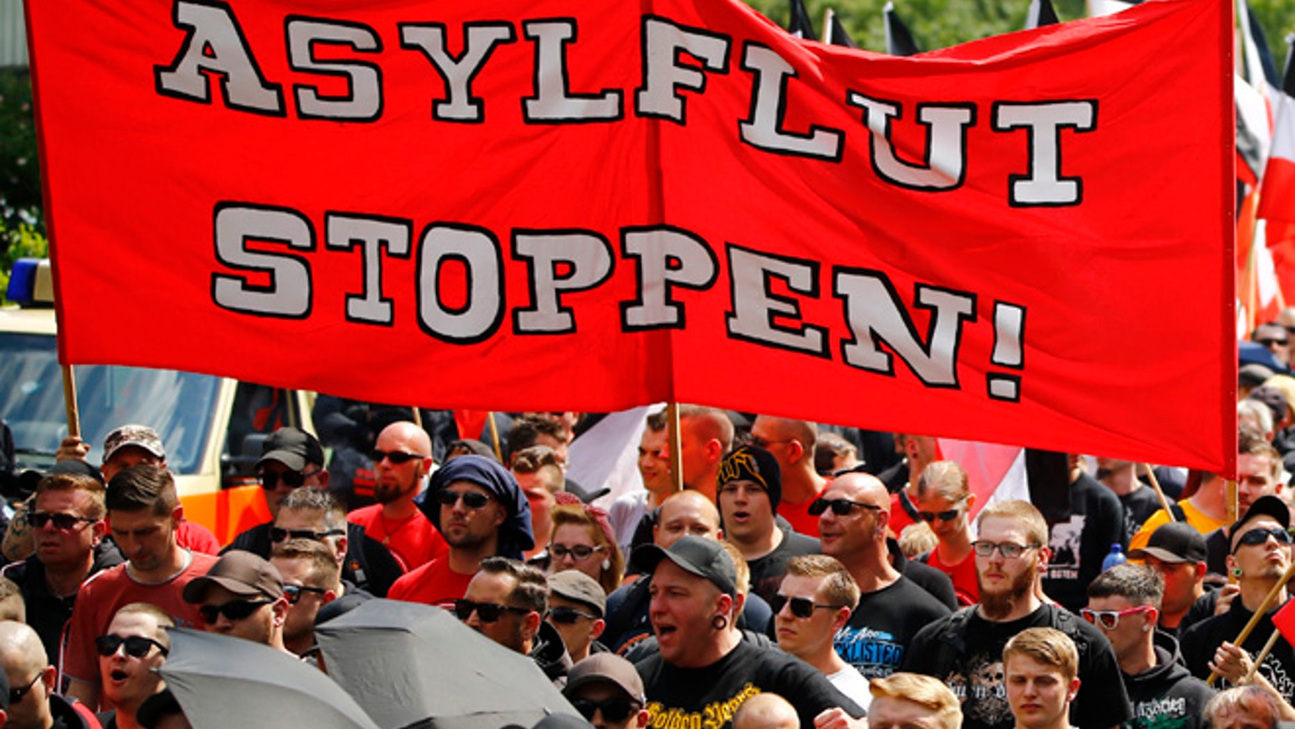 Far-right supporters hold up a banner reading ' stop the flood of asylum seekers' during a demonstration march in Dortmund, Germany