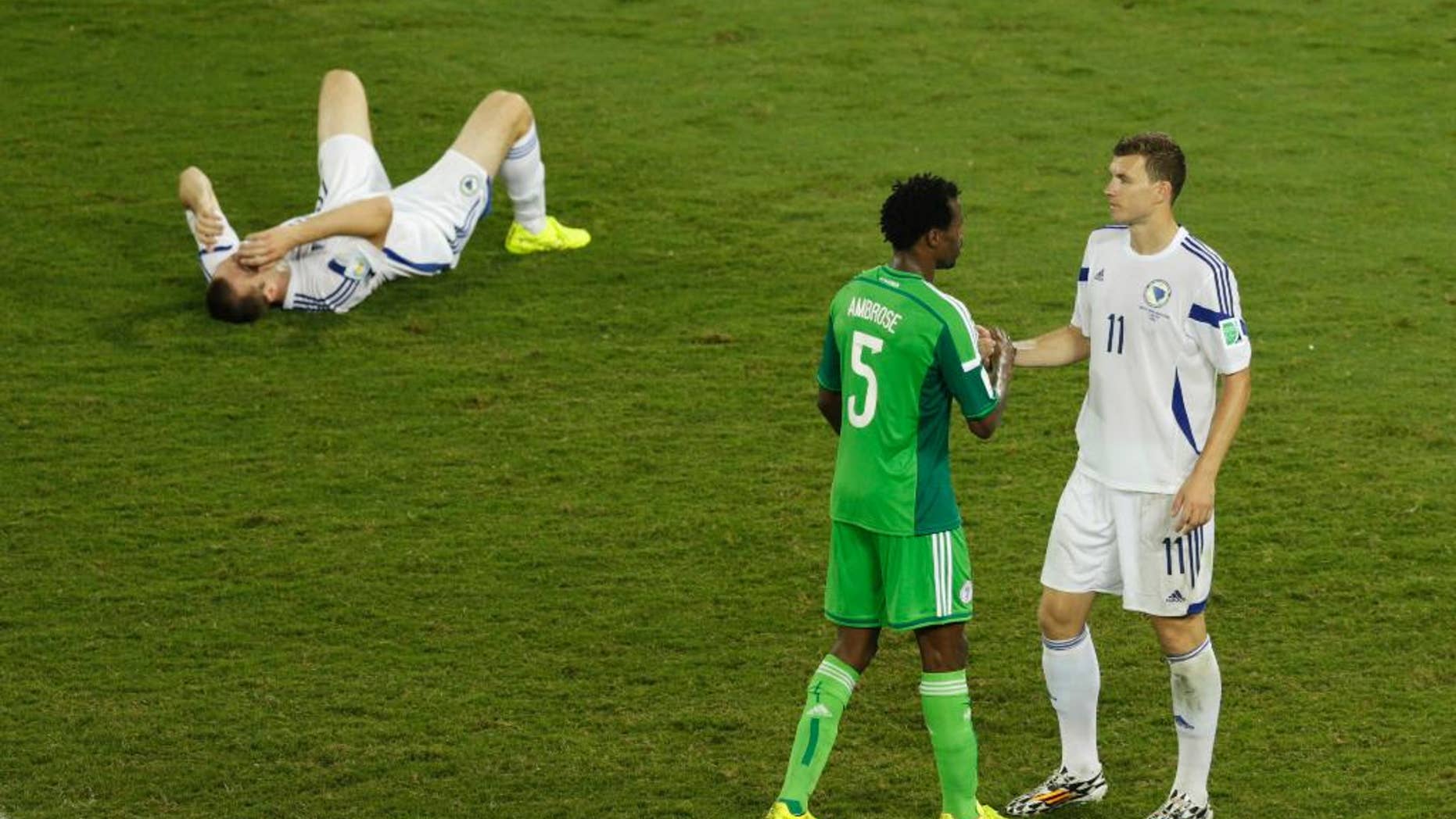 Bosnia's Edin Dzeko shakes hand with Nigeria's Efe Ambrose as Bosnia's goalkeeper Asmir Avdukic sits on the floor during the group F World Cup soccer match between Nigeria and Bosnia at the Arena Pantanal in Cuiaba, Brazil, Saturday, June 21, 2014. (AP Photo/Fernando Llano)