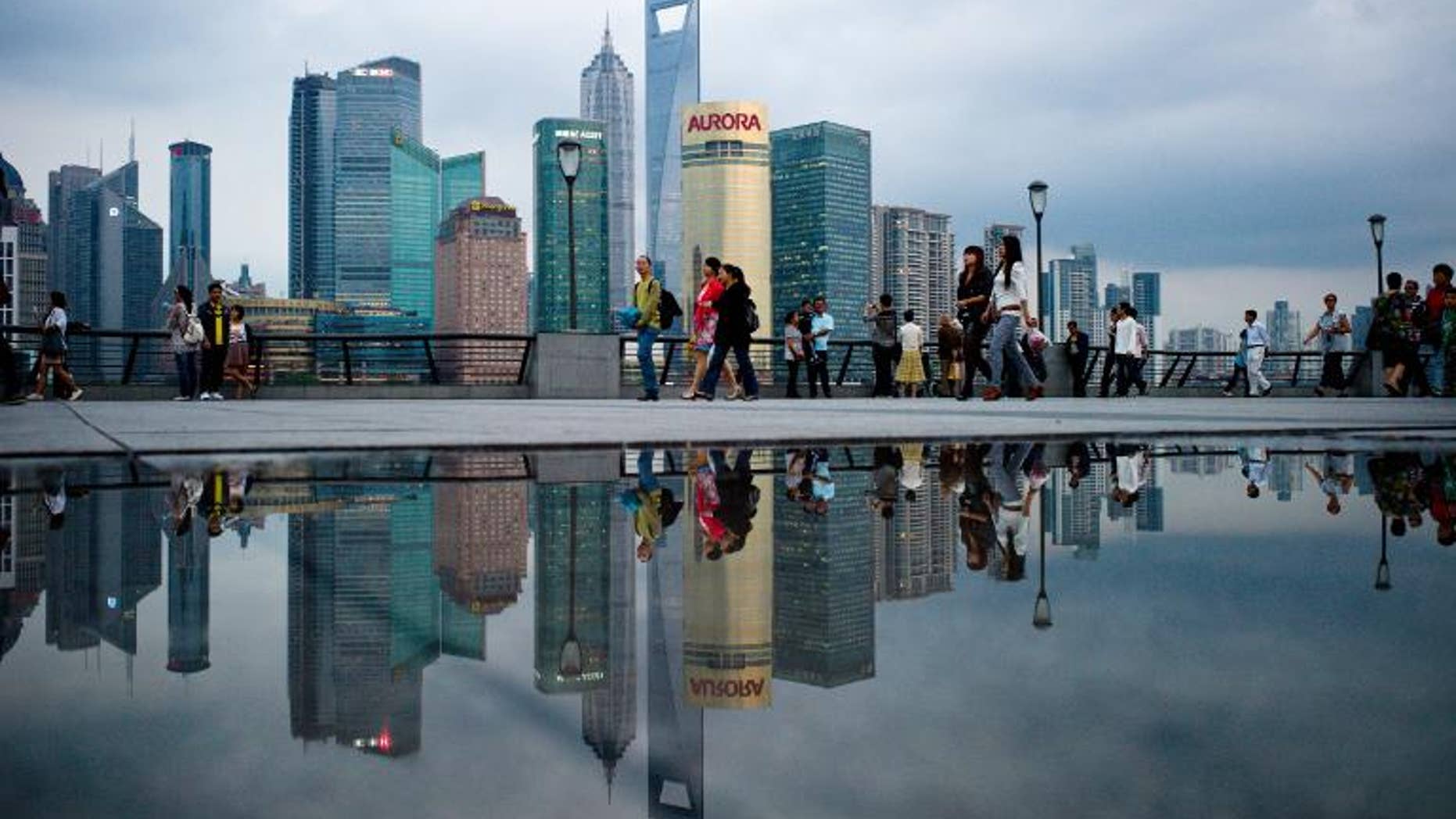 Pedestrians walk past the skyline of the city's financial district in Shanghai on October 8, 2010.