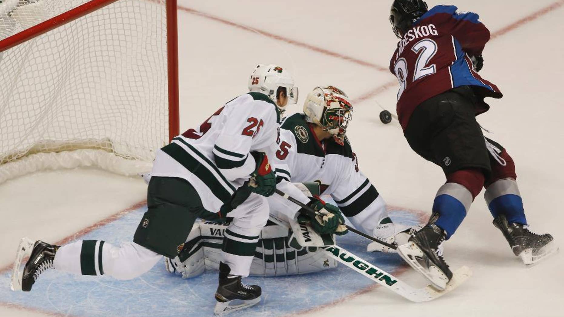 Colorado Avalanche left wing Gabriel Landeskog, right, of Sweden, flies past Minnesota Wild goalie Darcy Kuemper, center, as he stops shot while defenseman Jonas Brodin covers in the third period of the Wild's 3-0 victory in an NHL hockey game in Denver on Saturday, Oct. 11, 2014. (AP Photo/David Zalubowski)