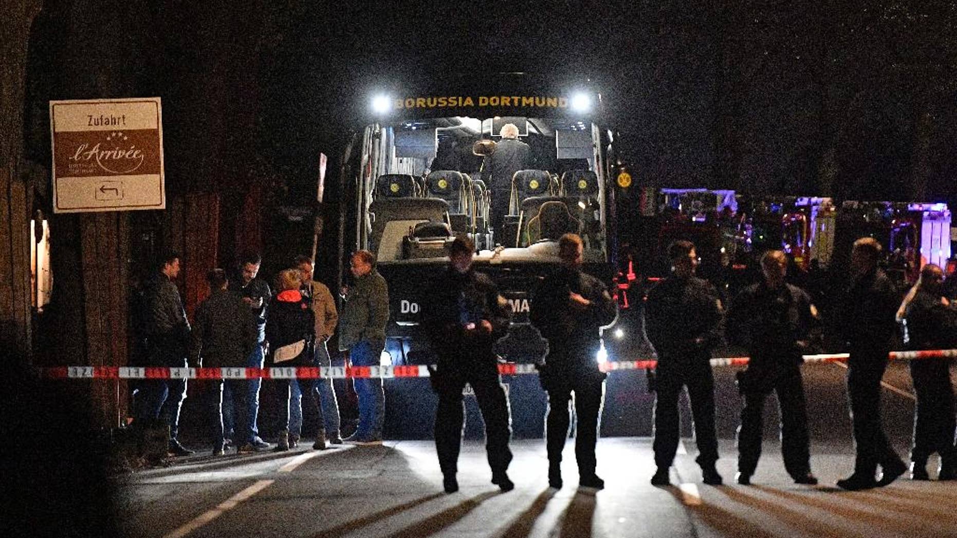 FILE - In this April 11, 2017 file photo police officers stand in front of Dortmund's damaged team bus after explosions which injured two people before the Champions League quarterfinal soccer match between Borussia Dortmund and AS Monaco in Dortmund, western Germany. (AP Photo/Martin Meissner, file)