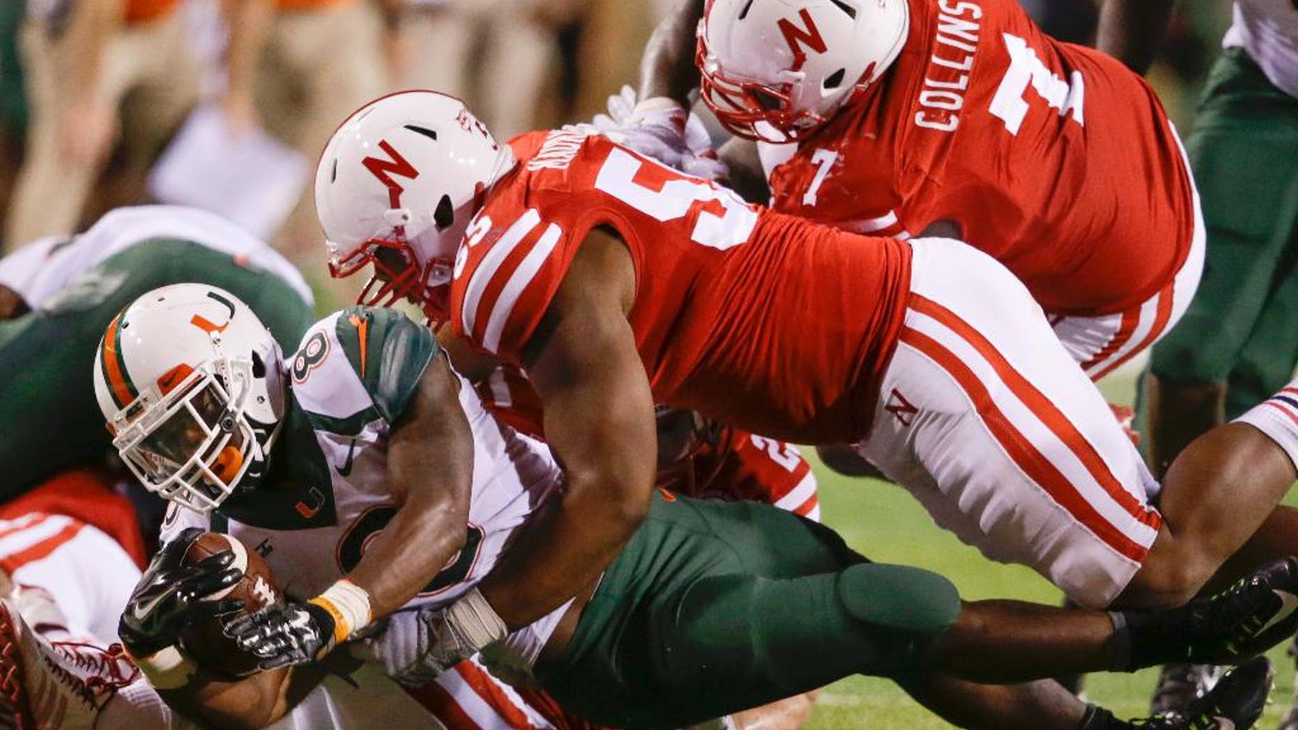 Miami running back Duke Johnson (8) is brought down by Nebraska defensive tackles Kevin Maurice (55) and Maliek Collins (7) in the second half of an NCAA college football game in Lincoln, Neb., Saturday, Sept. 20, 2014. Nebraska won 41-31. (AP Photo/Nati Harnik)