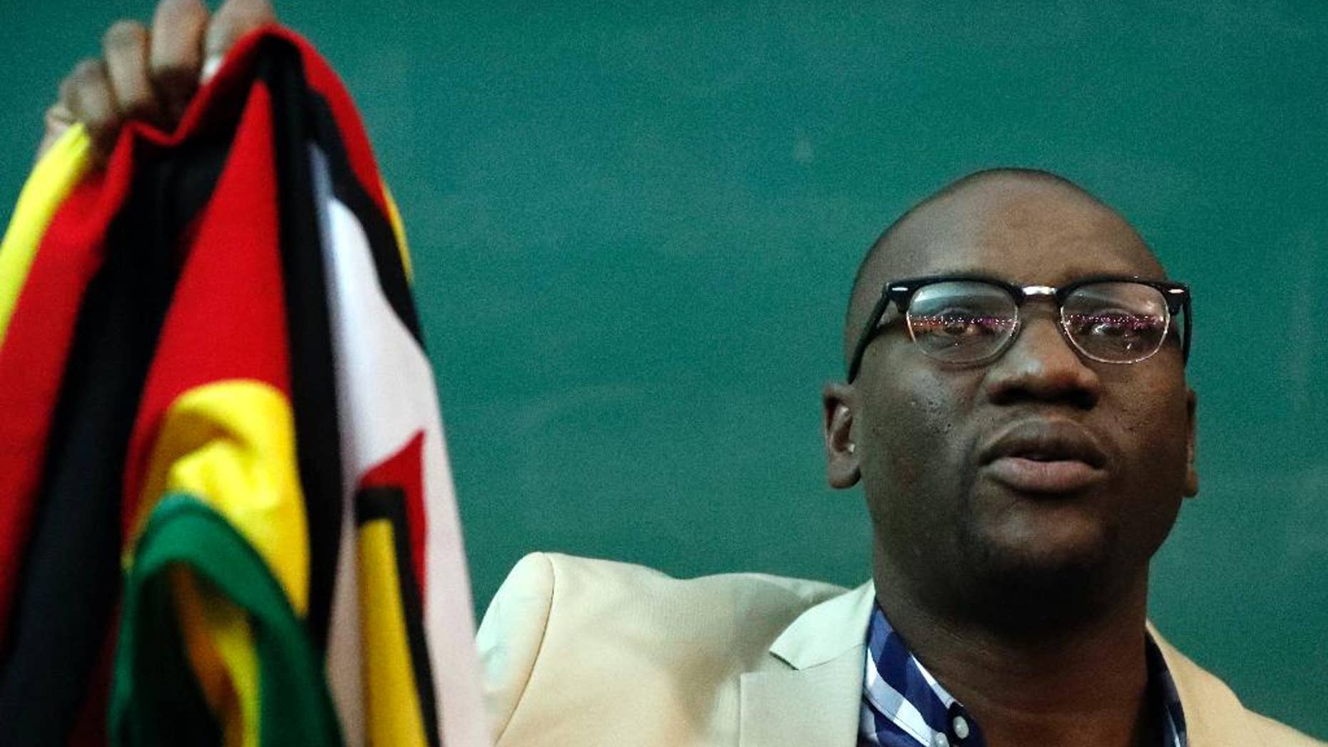 FILE - In this July 28, 2016 file photo, Zimbabwean pastor Evan Mawarire, holds his country's flag before addressing supporters at the University of the Witwatersrand in Johannesburg, South Africa. Mawarire, who is using social media to take on President Robert Mugabe's government, says he is afraid for his life and wants his countrymen to do everything possible to avoid bloodshed in their quest to reform the southern African country. In an interview with the Associated Press in Johannesburg on Monday, Aug. 8, 2016, he said Mugabe's ZANU-PF party was eating itself alive and there is very little that citizens of the country can do to fight it. (AP Photo/Themba Hadebe, file)