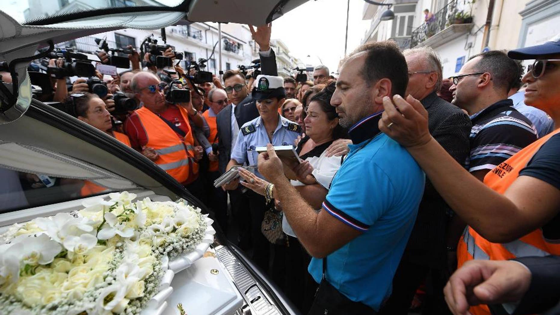 Members of the media crowd around the hearse of Tiziana Cantone as her mother Teresa Giglio, center, salutes it, during her funeral in Casalnuovo, near Naples, Italy, Thursday, Sept. 15, 2016. Italian prosecutors in Naples have opened an investigation into possible charges of instigation to suicide after a 31-year-old woman killed herself after failing in a long legal battle to get a pornographic video removed from the Internet. (Ciro Fusco/ANSA via AP)