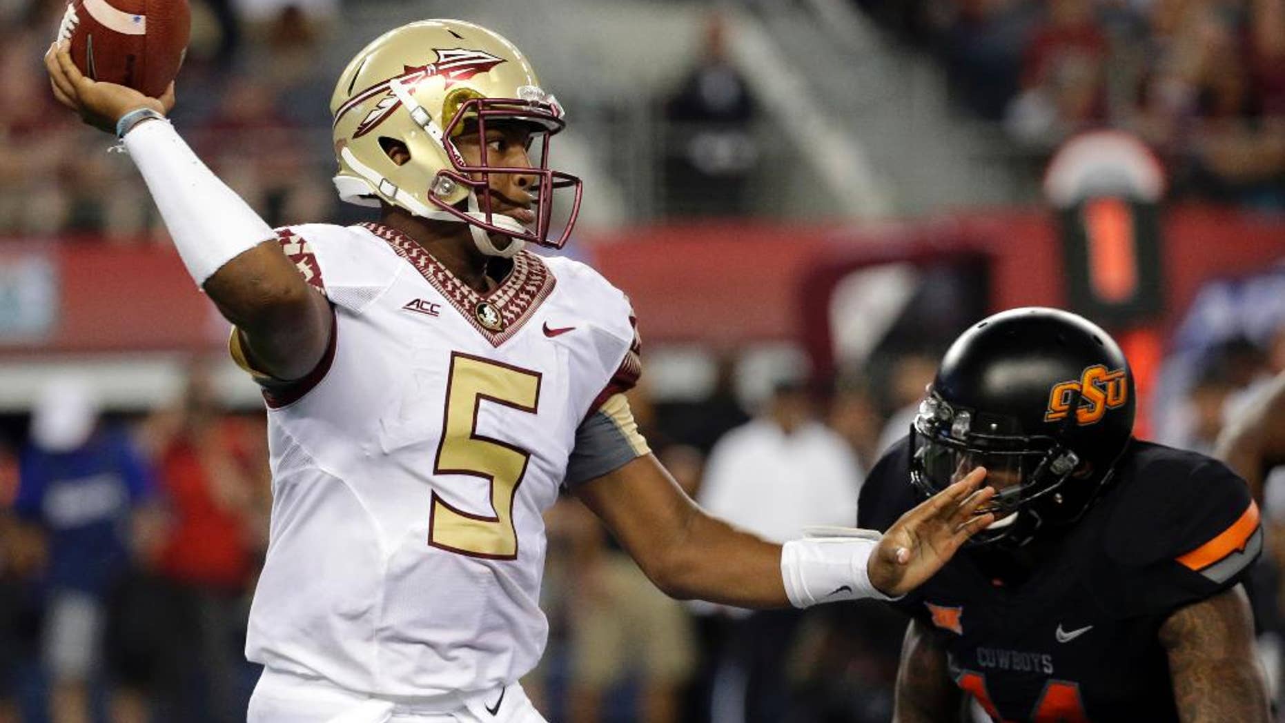 FILE - In this Aug. 30, 2014, file photo, Florida State quarterback Jameis Winston (5) passes under pressure from Oklahoma State linebacker Josh Furman (14) during an NCAA college football game in Arlington, Texas. Things didn't come nearly as easy for the Heisman winner, and the FSU offense will need to play much better if the Seminoles are to win the first College Football Playoff. (AP Photo/Tony Gutierrez, File)
