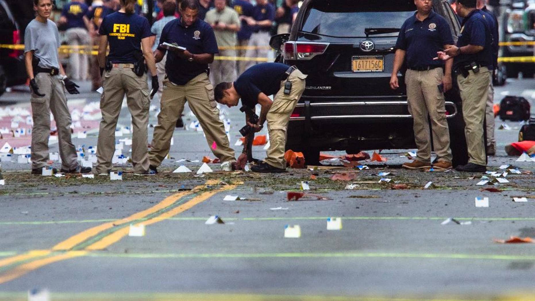FILE - In this Sunday, Sept. 18, 2016, file photo, members of the Federal Bureau of Investigation (FBI) carry on investigations at the scene of Saturday's explosion in Manhattan's Chelsea neighborhood, New York. Investigators probing bomb blasts in New Jersey and New York believe they've identified two men who walked off with a bag abandoned by the bomber on a street as Egyptian tourists. (AP Photo/Andres Kudacki, File)