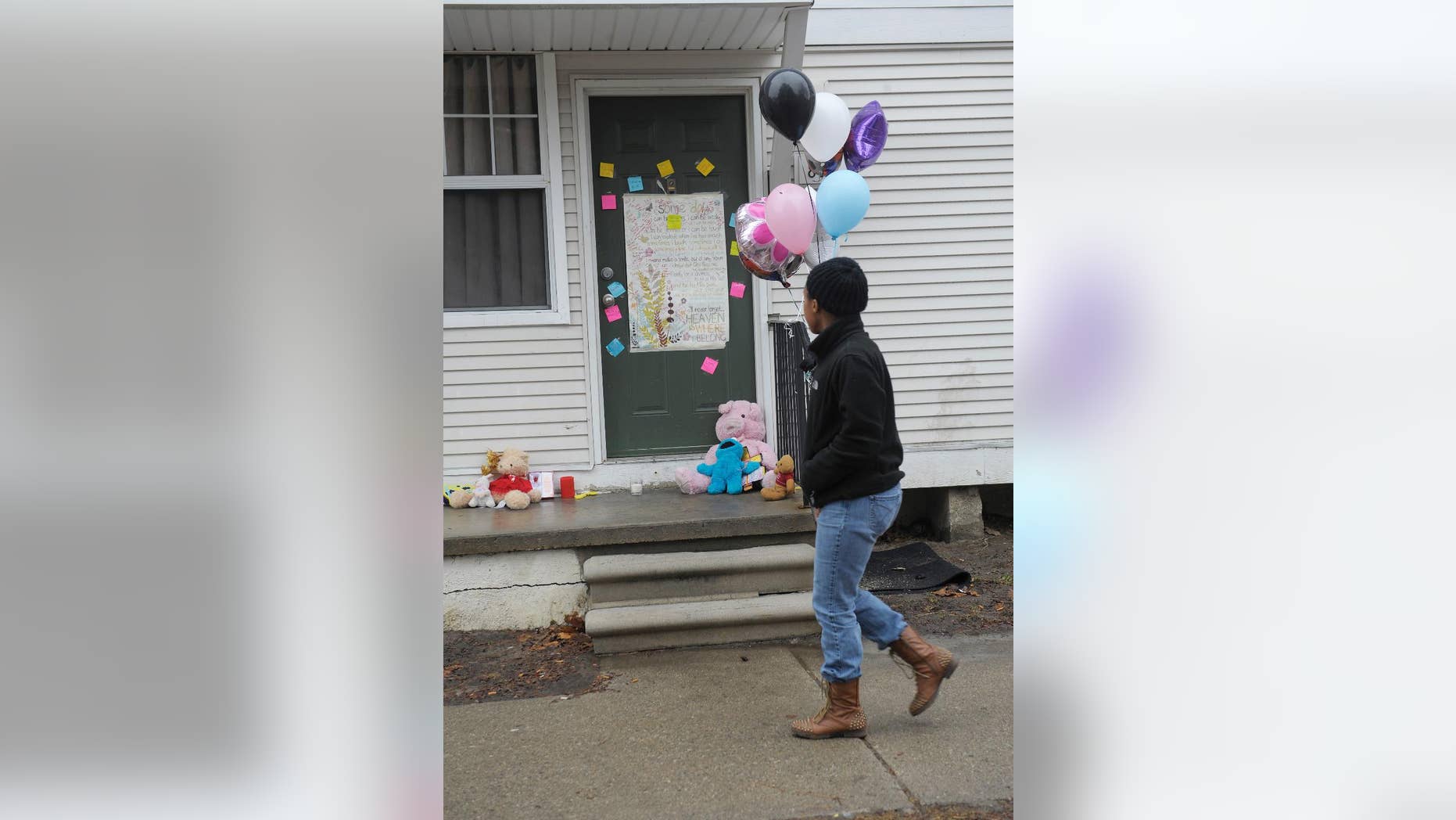 A woman walks past notes left on the door at a town home in Detroit, Wednesday, March 25, 2015, where two bodies were found. A Detroit mother was arrested Tuesday after the frozen bodies of a boy and girl were found in a deep freezer in the family's home, police said. Court officers found the children's bodies while carrying out an eviction order at the 3-bedroom home in the apartment complex. (AP Photo/Detroit News, Clarence Tabb Jr.) DETROIT FREE PRESS OUT; HUFFINGTON POST OUT; MANDATORY CREDIT