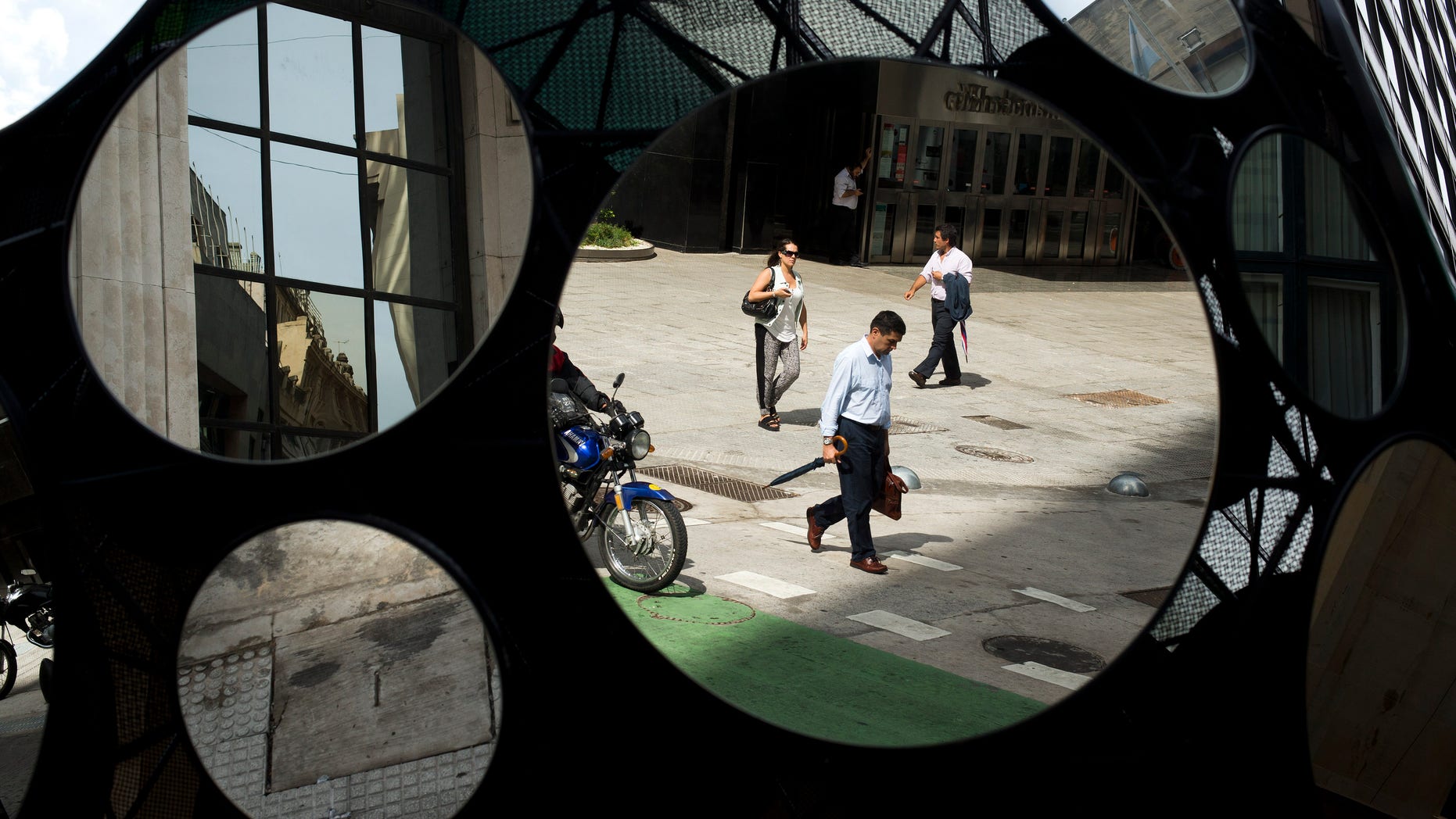FILE - In this Tuesday, Jan. 28, 2014 file photo, office workers are reflected in a building's decorative mirrors in downtown Buenos Aires, Argentina. When Argentina fell into the economic abyss a decade ago after defaulting on its sovereign debt, Brazil suffered right along with it, nearly following its neighbor into insolvency. Now, with Argentina's economy again facing a currency plunge and inflation spike, its ability to inflict economic damage on Brazil has greatly diminished. (AP Photo/Victor R. Caivano, File)