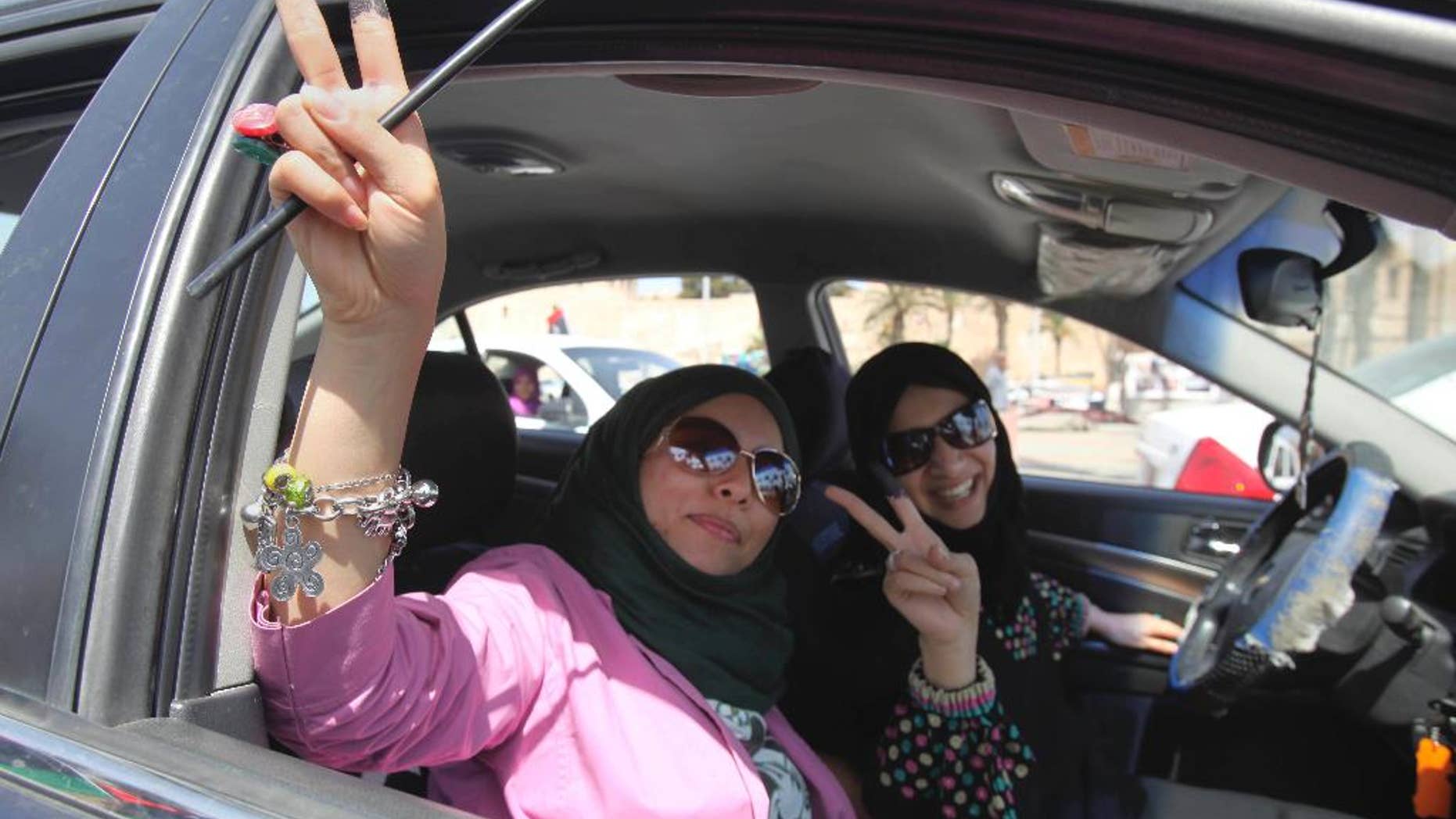 FILE -- In this July 7, 2012 file photo, Libyan women hold up their ink-marked fingers that shows they have voted as they drive in Tripoli, Libya. Eastern Libyan military authorities issued a ban Thursday, Feb. 16, 2017, on women from traveling outside the country without a male guardian, sparking mockery. The decision was issued by the Libyan Chief of Staff Abdel-Razek al-Nadhouri, the military ruler of eastern Libya. He was appointed by the army chief Khalifa Hifter who is allied with the internationally-recognized parliament. (AP Photo/Abdel Magid Al Fergany, File)