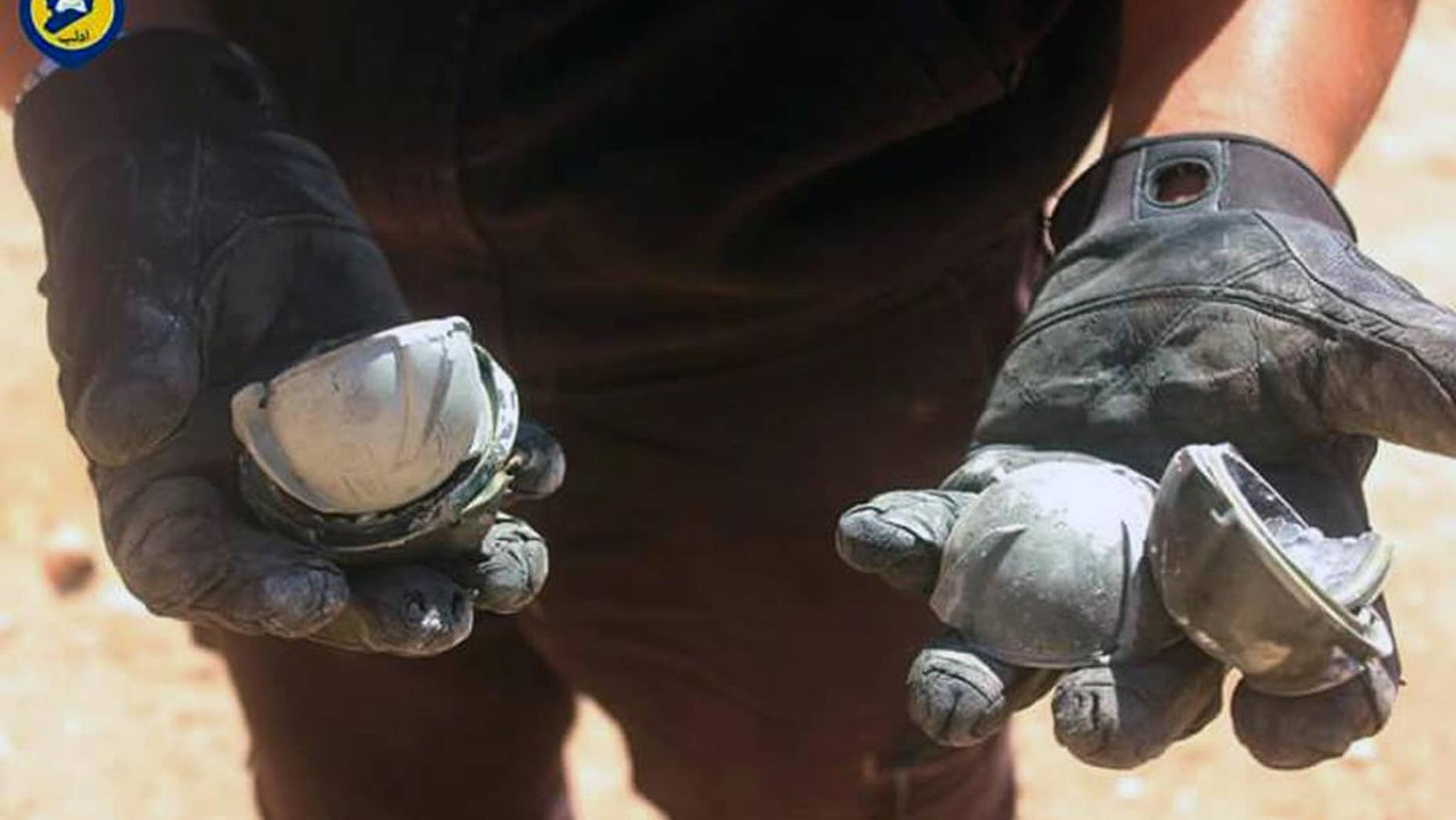 In this photo provided by the Syrian Civil Defense group known as the White Helmets, shows a member of Civil Defense displays the cluster bombs in the Khan Sheikhoun neighborhood of Idlib, Syria, Thursday, Sept. 29, 2016. The U.S. and Russia escalated their war of words over Syria Thursday as government forces kept up their assault on Aleppo's rebel-held quarters and registered tenuous gains. (Syrian Civil Defense White Helmets via AP)