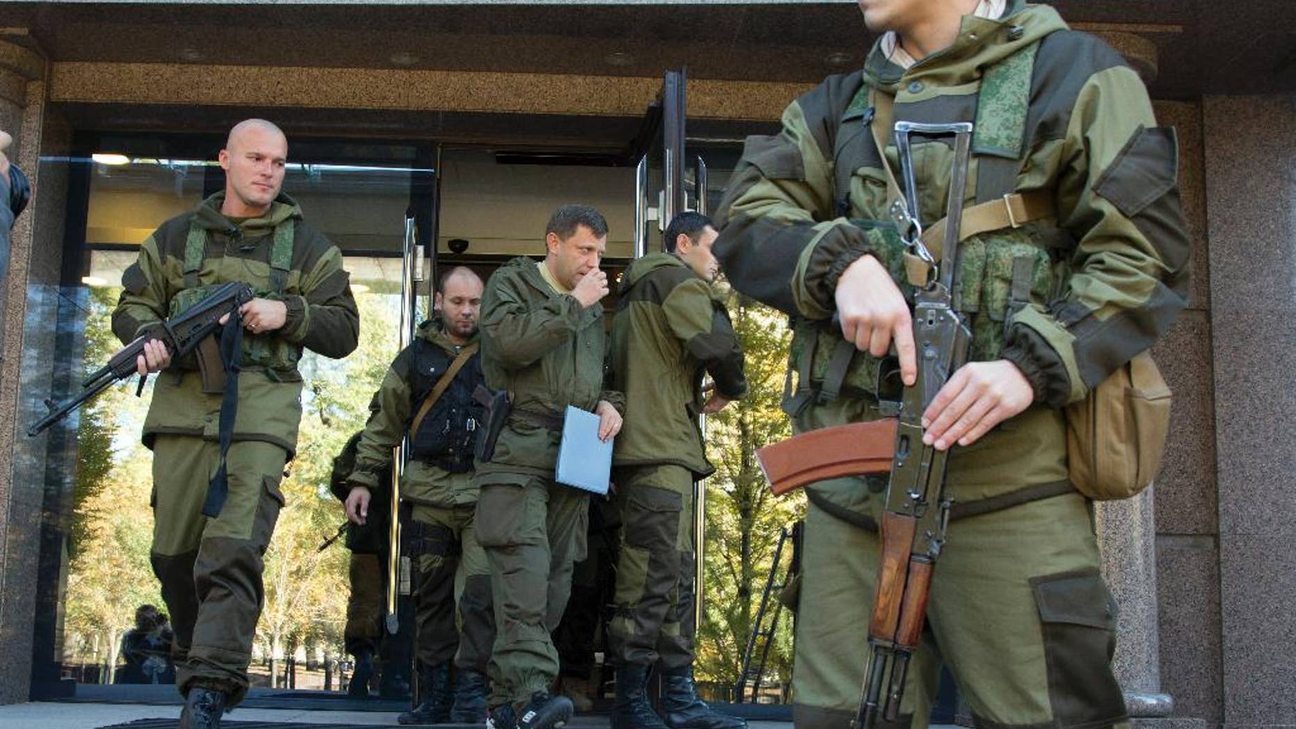 Alexander Zakharchenko, Prime Minister of the self proclaimed 'Donetsk People's Republic', centre, surrounded by pro-Russian rebels, walks in the town of Donetsk, eastern Ukraine Saturday, Oct. 11, 2014. A pro-Russian rebel leader says they have signed a demarcation deal with the Ukrainian government which sees the Ukrainians give up several villages including the one next to a strategic airport. (AP Photo/Dmitry Lovetsky)
