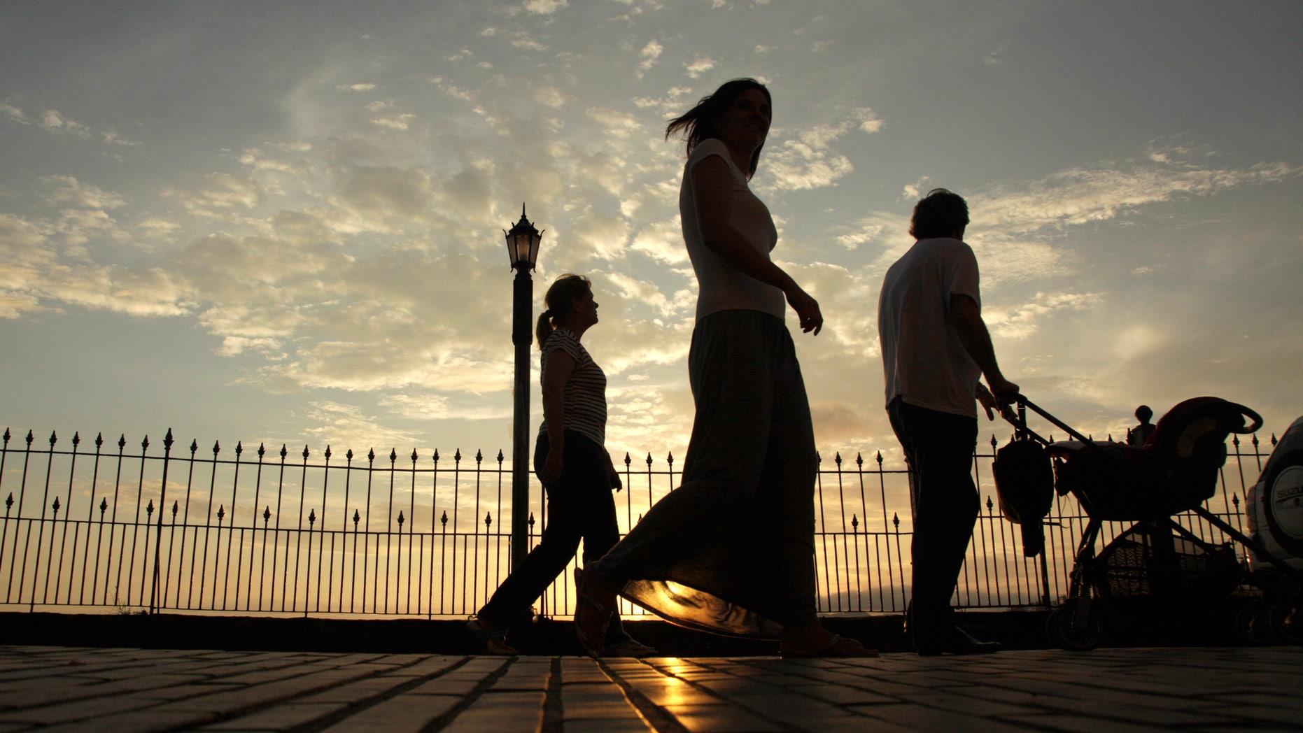 People walk during the sunset in Panama City. (AP Photo/Arnulfo Franco)