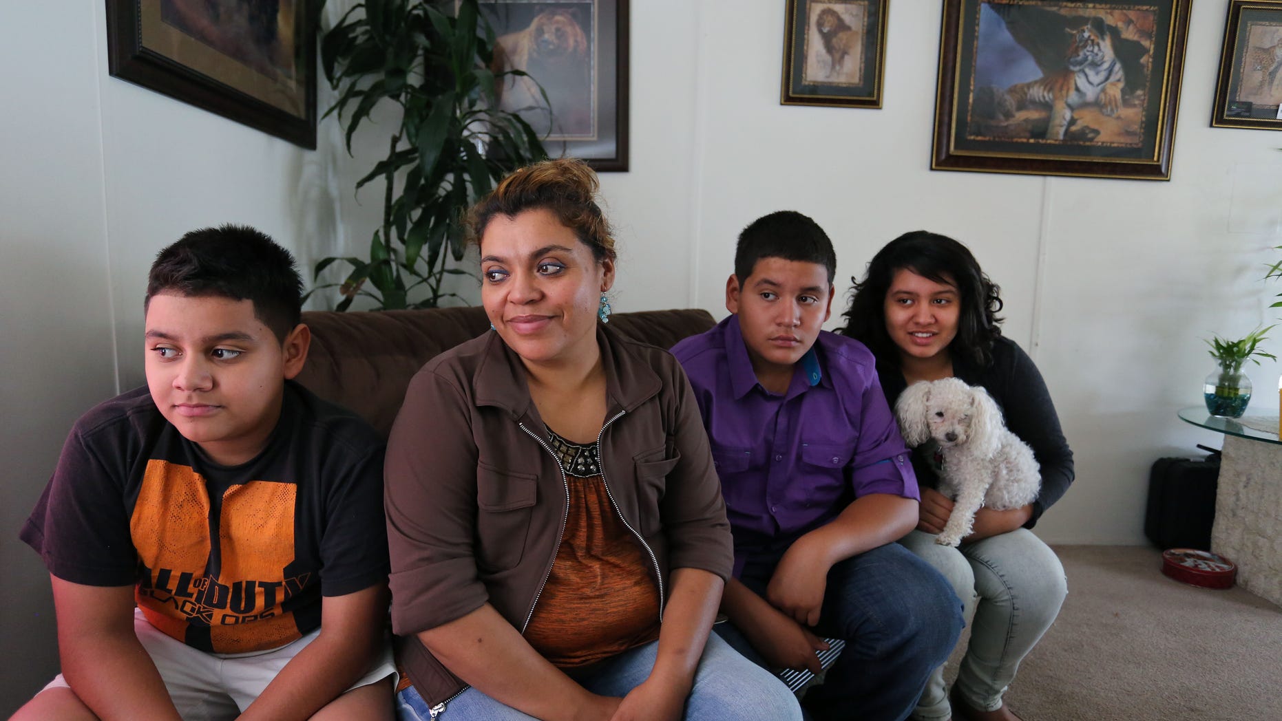 Adriana Gaytan, who came to Colorado in 1997 from the Mexican state of Zacatecas, second from left, sits at home with her children who were born in the U.S. from left to right, Osbaldo, 11, Oscar 13, Indhira, 14, and their dog Kissy, in Aurora, Colo., Thursday July 31, 2014. Gaytan will get a drivers license soon, as Colorado will begin issuing driver's licenses and identification cards to people who are in the country illegally or have temporary legal status. (AP Photo/Brennan Linsley)
