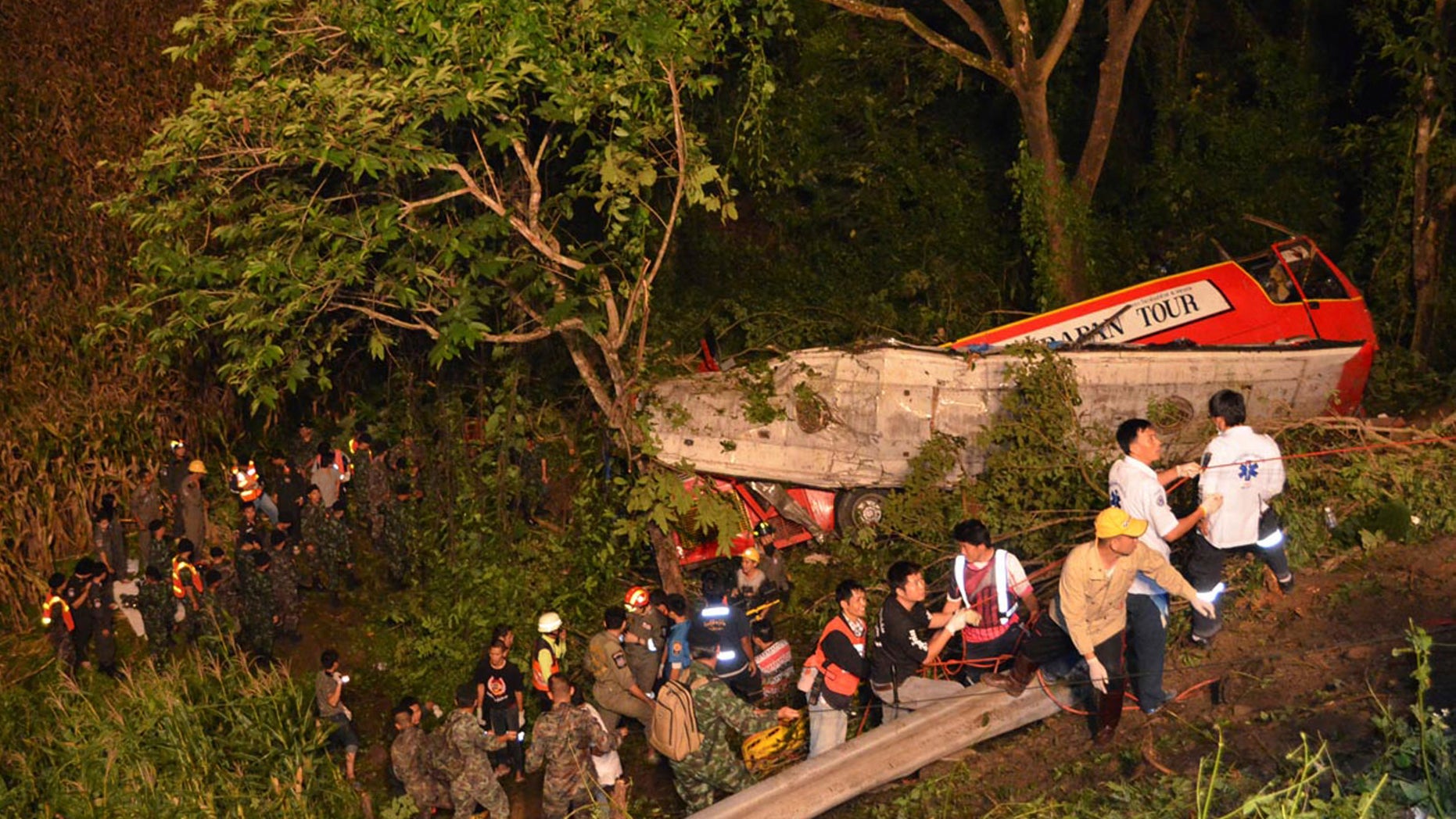 In this photo taken Wednesday, Oct. 23, 2013, Thai rescuers search for passengers of a bus that fell about 30 meters (98 feet) into the ravine on a curvy rural road in Lampang province, Thailand. The bus carrying worshippers home from a temple at the end of Buddhist Lent plunged into a ravine in northern Thailand, killing 22 passengers, police said Thursday. (AP Photo/Daily News) THAILAND OUT