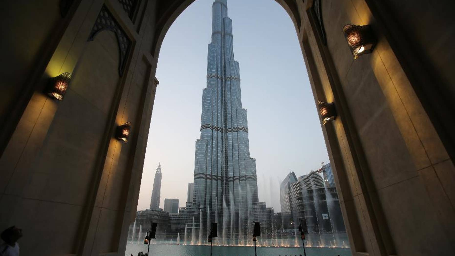 FILE - In this Monday, April 13, 2015, with the world tallest tower, Burj Khalifa, in the background, tourists and visitors watch and take photos of the Dubai Fountain in Dubai, United Arab Emirates. The Burj Khalifa announced Thursday, Nov. 5, it is selling tickets on the United Arab Emirates' weekend of Friday and Saturday for sunrise viewings. (AP Photo/Kamran Jebreili, File)