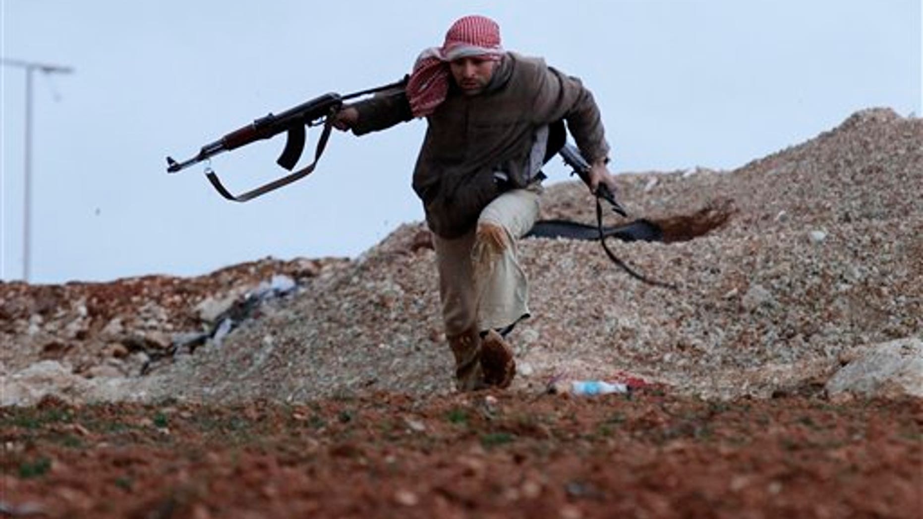 Feb. 8, 2012: A Syrian rebel runs for cover during an exchange of fire with army troops, unseen, in Idlib, Syria.