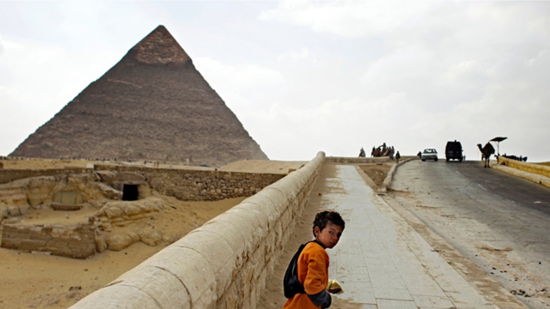 March 23: A young souvenir vendor walks along an almost empty road to the Giza pyramids on the outskirts of Cairo, Egypt.
