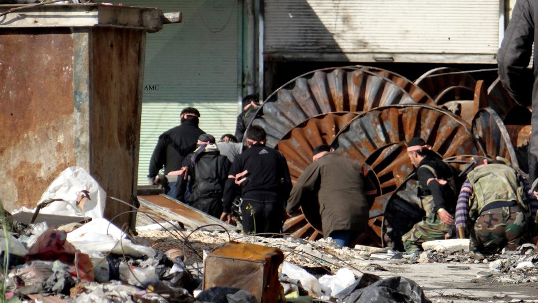 This citizen journalism image provided by Aleppo Media Center AMC which has been authenticated based on its contents and other AP reporting, shows members of the free Syrian Army hiding behind scrap metal during an attack against Syrian government forces, in the neighborhood of al-Amerieh in Aleppo, Syria, Sunday, April. 21, 2013. The Syrian opposition called on Hezbollah to withdraw its fighters from the country immediately, as activists said regime troops supported by pro-government gunmen linked to the Lebanese Shiite militant group battled rebels Sunday for control of a string of villages near the Lebanon-Syria border. (AP Photo/Aleppo Media Center AMC)